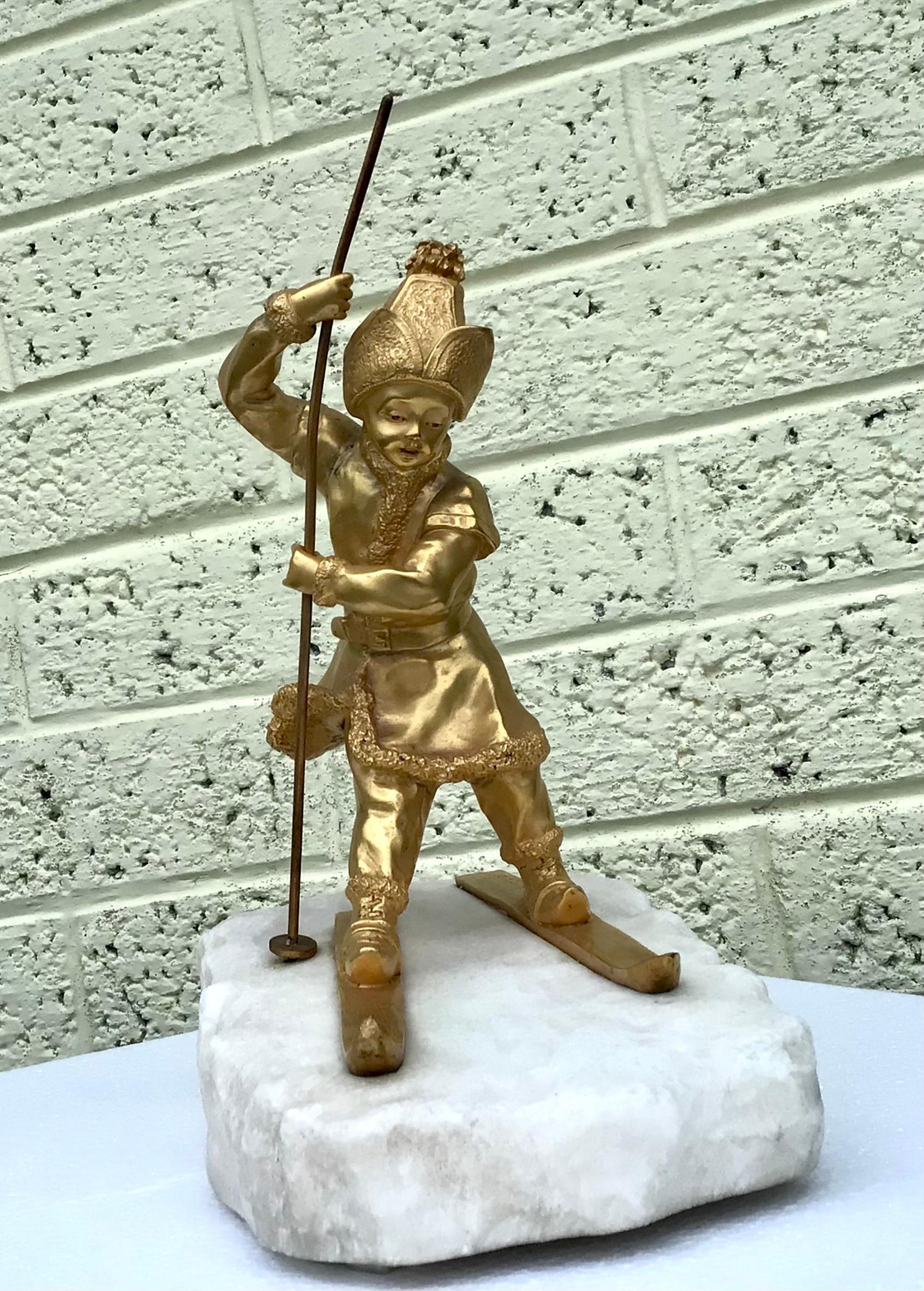 Charlotte Monginot 
(1872 Paris - 1962 Neuilly-sur Seine) Junger Skifahrer Vergoldete Bronze; geschnitzt; Metallstab; Sockel aus Alabaster. Zweimal in der Bronze und im Sockel signiert; Vollständig vergoldete Bronzedarstellung eines Jungen in