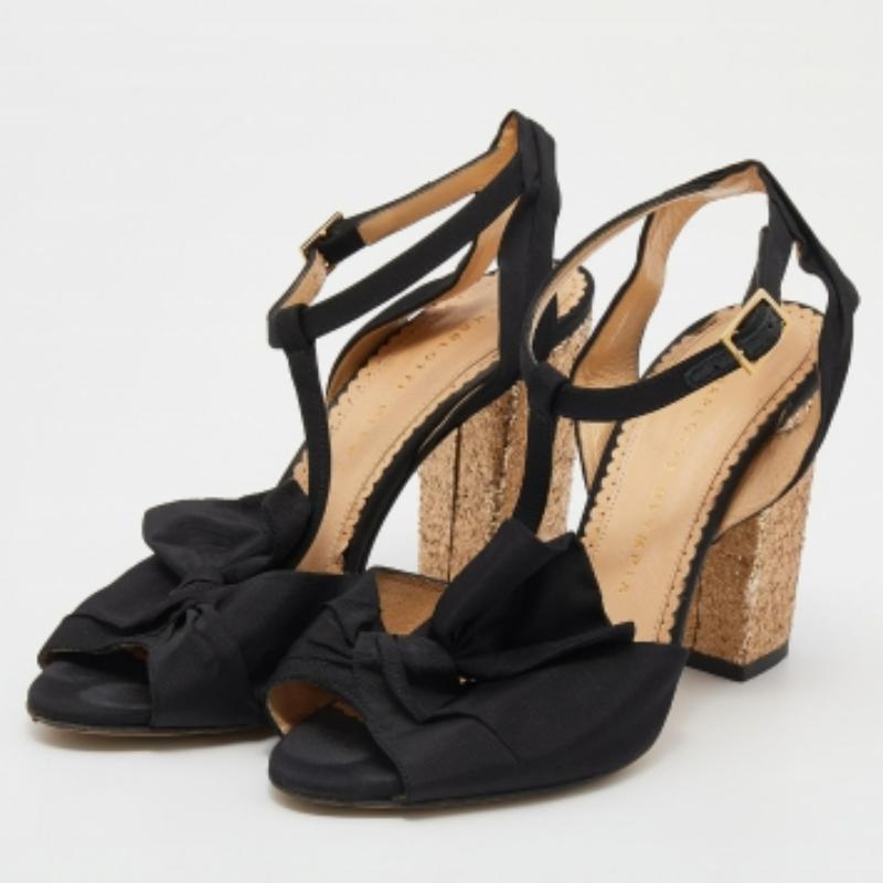 Charlotte Olympia ne manque pas d'occasions de nous impressionner et, une fois de plus, elle le fait avec ces superbes sandales ! Ces sandales noires ont été confectionnées en tissu et sont dotées de brides en T sur le devant. Elles arborent un