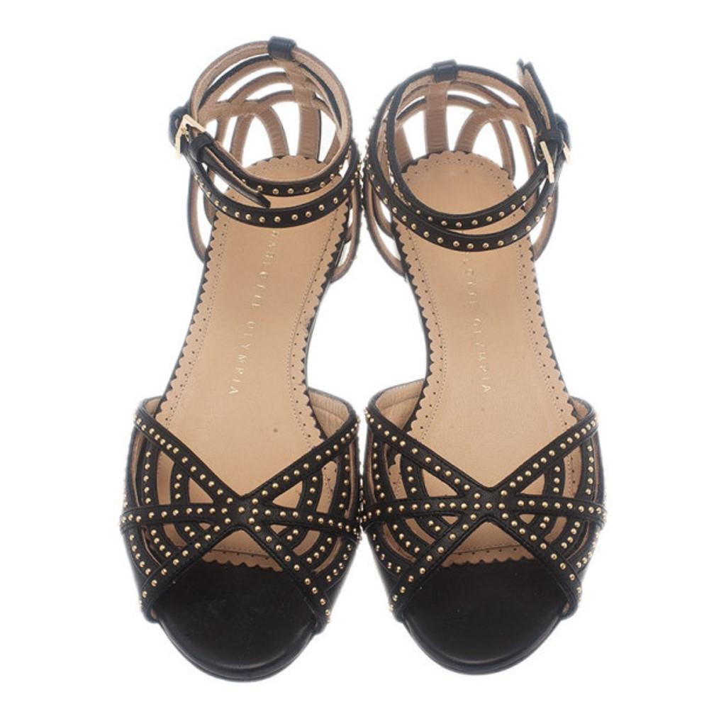 Ces sandales Charlotte Olympia s'associeront parfaitement à tous les looks. Confectionnés en cuir noir souple, ils présentent des motifs à lanières sur leur empeigne, agrémentés de clous dorés. Ils ont des sangles de cheville assorties, réglables