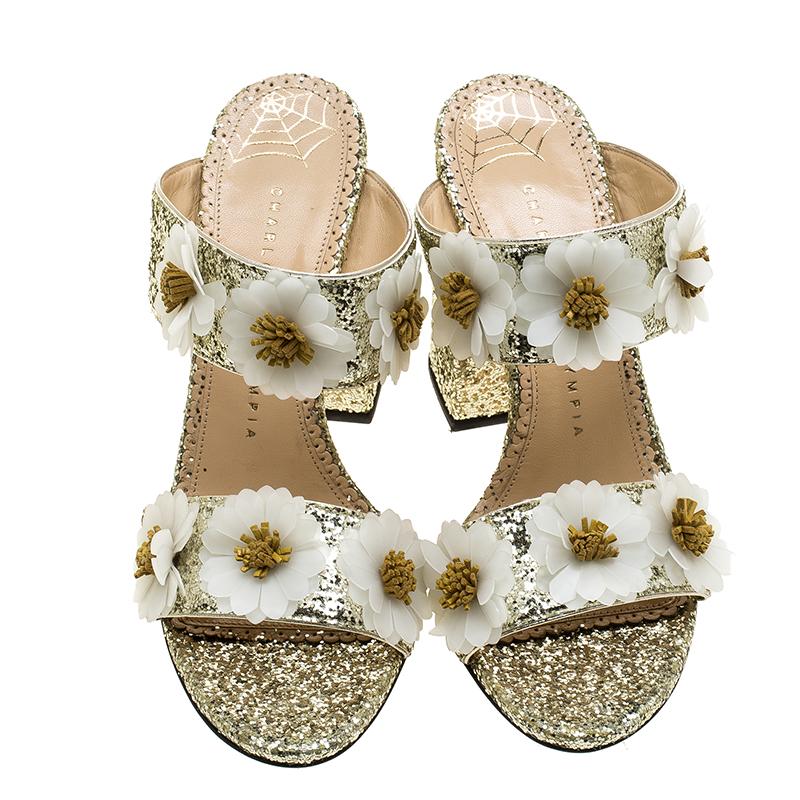 These slides from Charlotte Olympia have come straight from a shoe lover's dream. Designed with glitter straps, floral appliques and 10 cm black heels, the slides can be worn with any chic outfit of your choice.

Includes: Original Box, Original