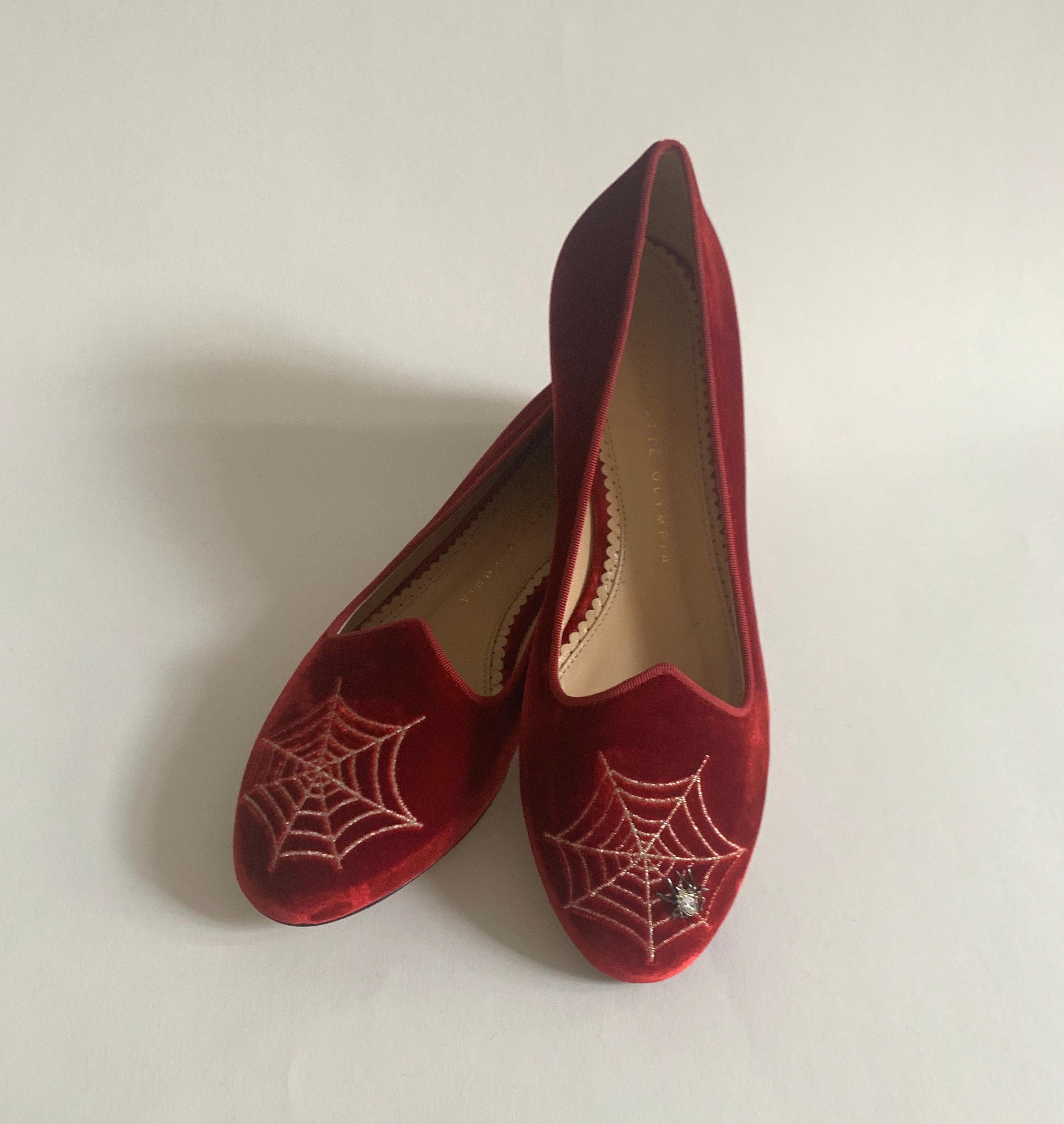 Charlotte Olympia red velvet flat features metallic spiderwebs in embroidered needlepoint at toes. A tiny spider with crystal embellishment creeps across one of the webs. Gold tone heel. Velvet slide with leather soles. Slide on. 

Made in