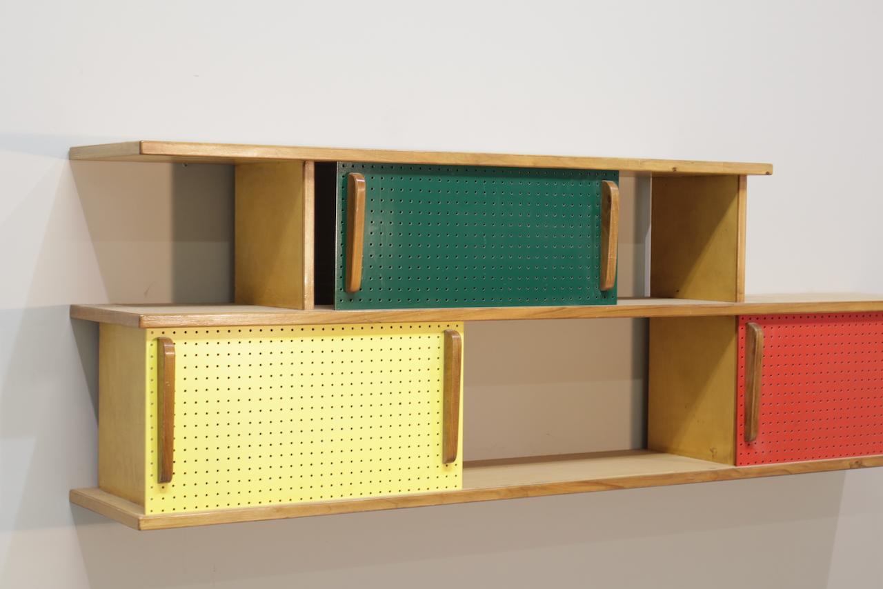Librería colgante Charlotte Perriand años 50. Fabricación francesa en madera y rojo y verde y amarillo  madera pintada.
En muy buen estado, ligero desgaste por el tiempo y el uso.