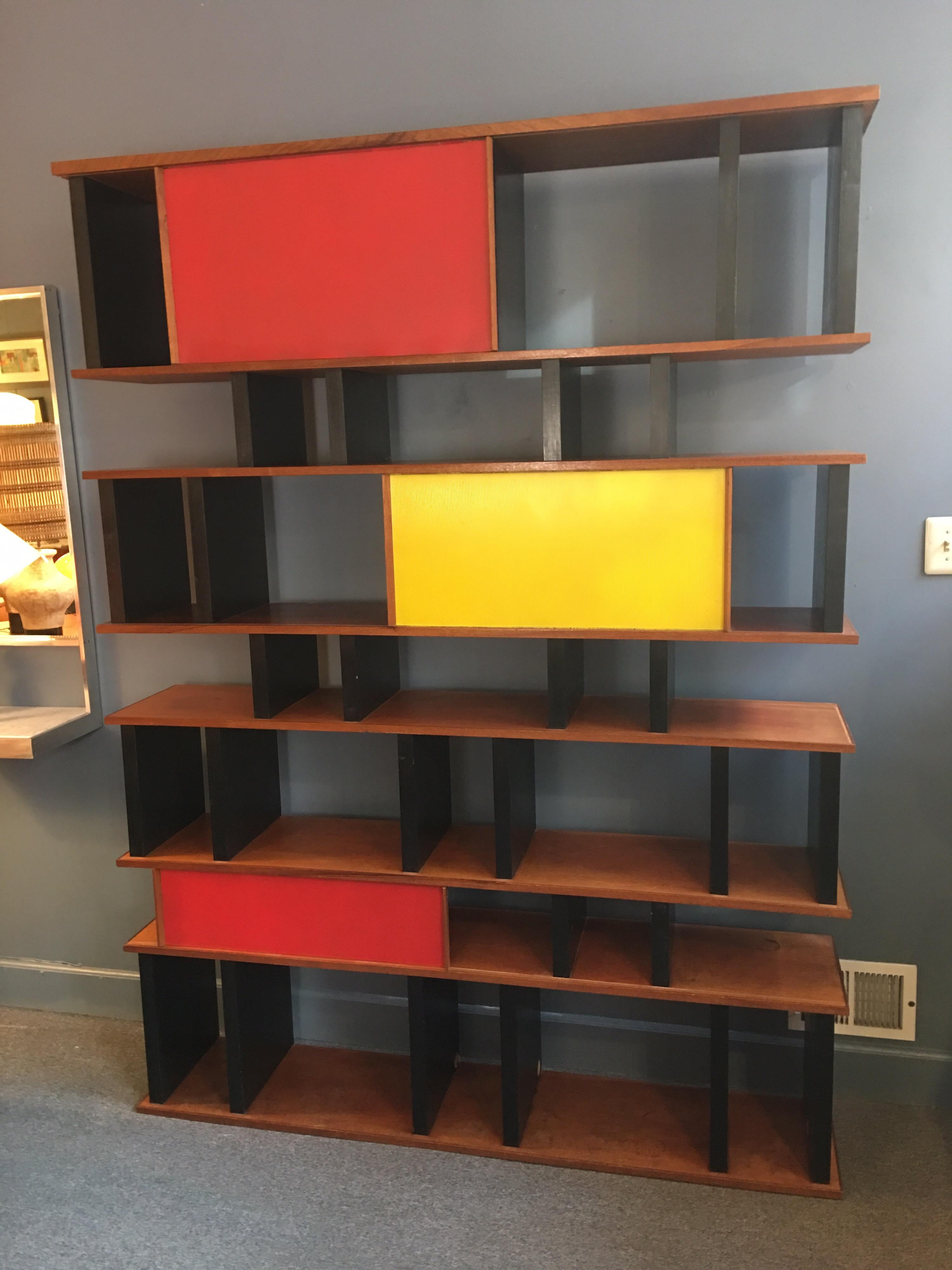 Perriand and Prouve style shelving system custom built for an East Village Bar in, circa 1999. Sliding doors move back and forth and can be left in multiple spots to conceal content. Bright door panels in yellow and red. Can hold an entire Library