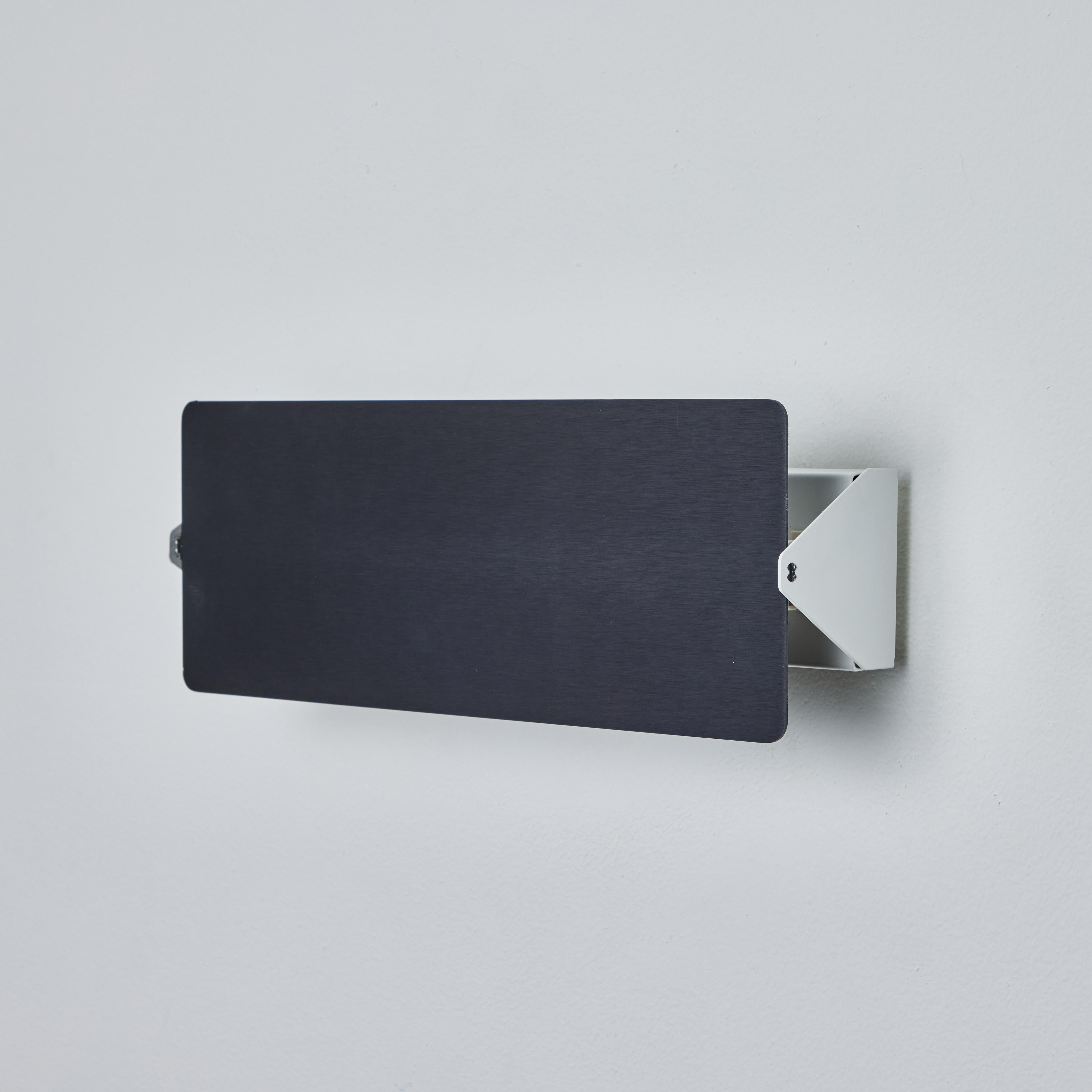 Charlotte Perriand 'Applique À Volet Pivotant Double' Wandleuchte in schwarz. Ein klares und ikonisches Design aus schwarz eloxiertem Aluminium und weiß lackiertem Metall. Als Teil einer Beleuchtungsserie, die in den 1950er Jahren mit der ikonischen
