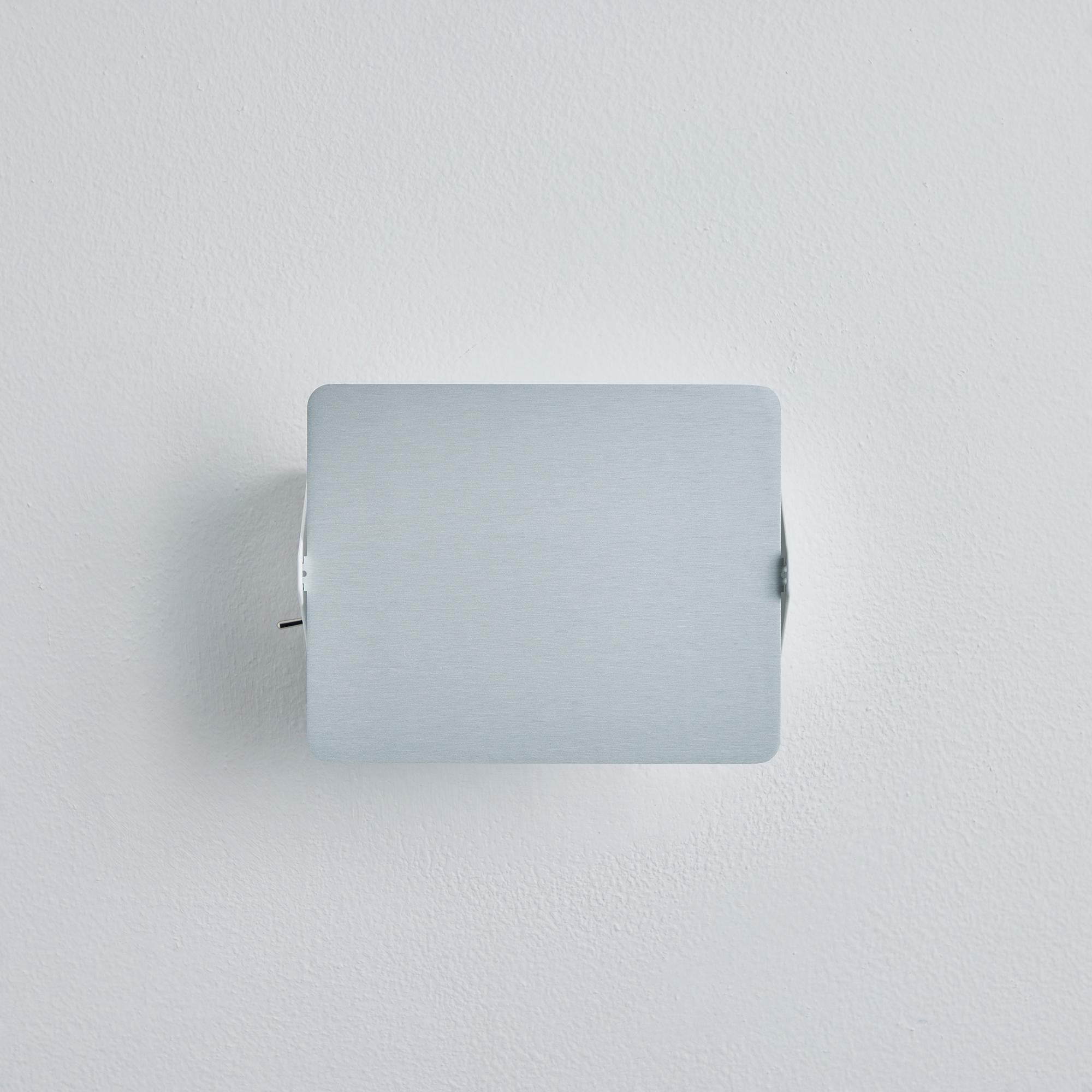 Charlotte Perriand 'Applique à Volet Pivotant' Wandleuchte aus Aluminium natur. Ein klares und ikonisches Design aus natürlich eloxiertem Aluminium und weiß lackiertem Metall. Ursprünglich in den 1950er Jahren als ikonische CP1 entworfen, werden
