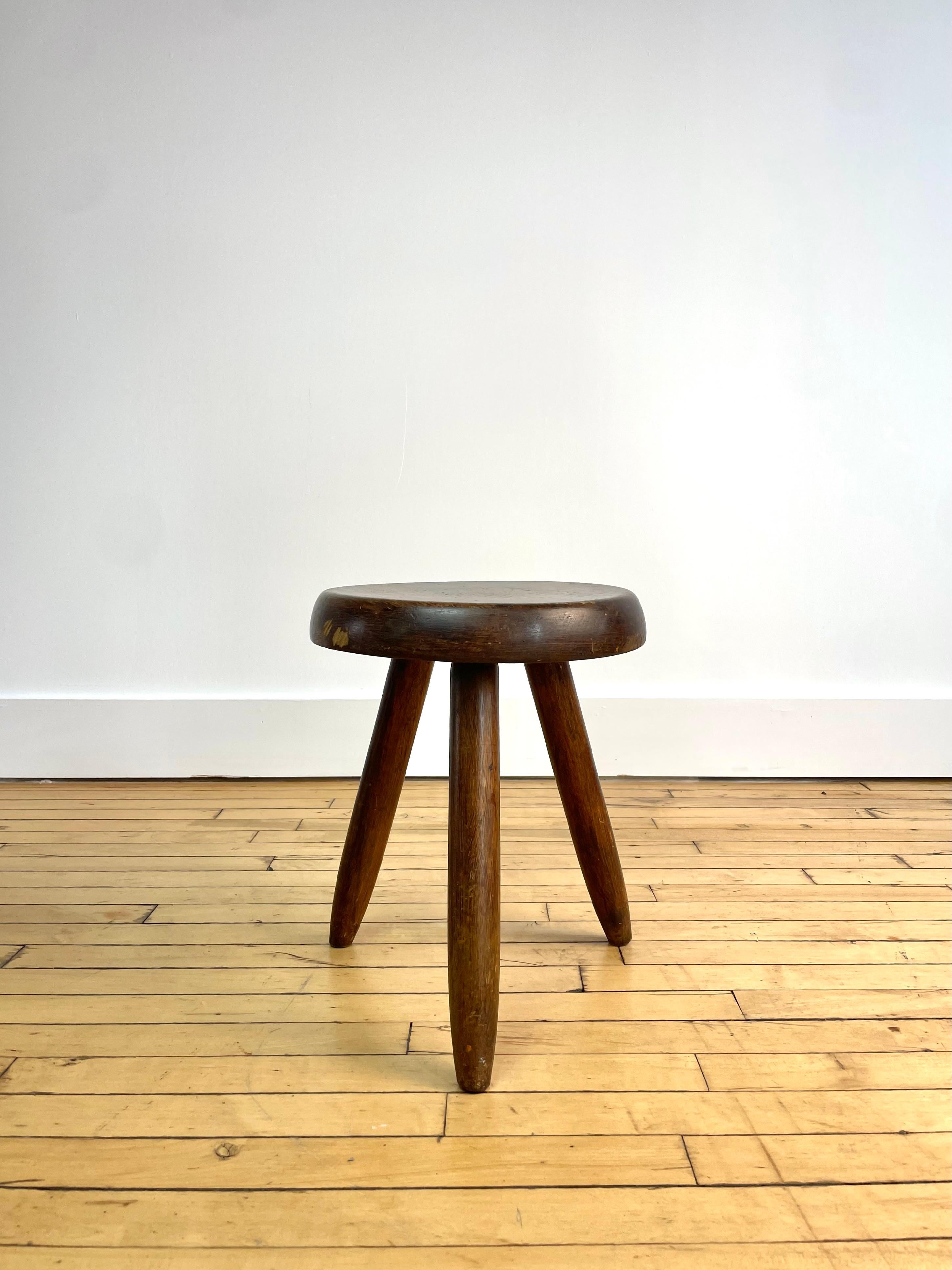 A beautiful example of Charlotte Perriand's Berger stool--her famous modernist interpretation of the classic tripod wood milking stool. 

This particular stool shows considerable wear and age. 

These simple and elegant stools were produced in