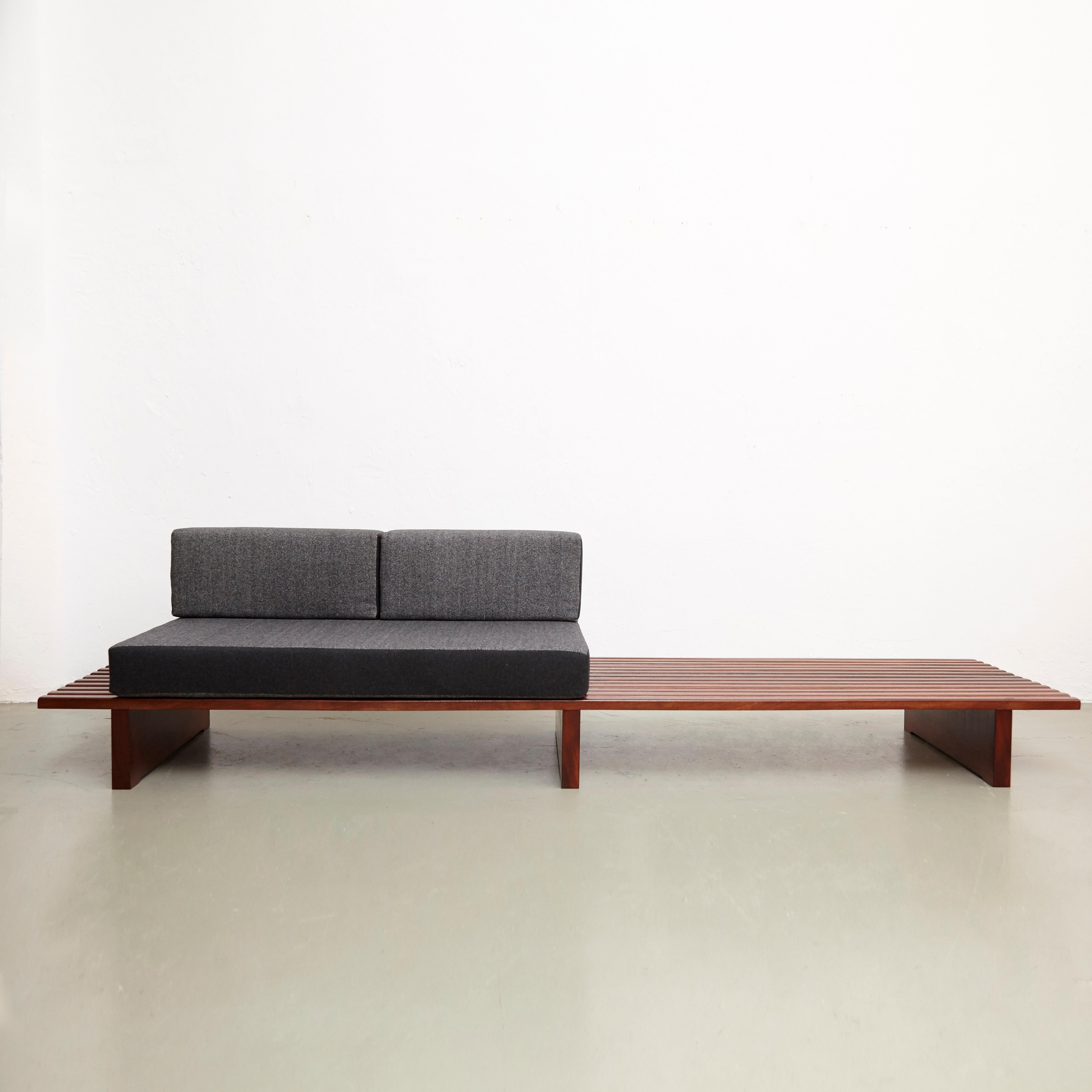 Bench designed by Charlotte Perriand, circa 1950.
This model is with 13 slats of wood.

Mahogany wood base and structure.

Wooden legs seem to be latter added by the previous owner.

The cushions have been produced now according to the