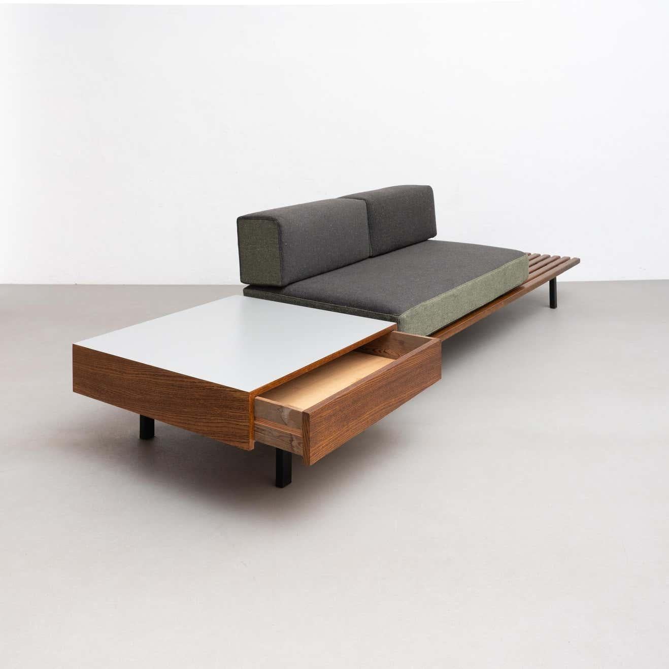This stunning bench with drawer was designed by the renowned French designer Charlotte Perriand in 1958, while working on a project in Cite Cansado, Mauritania. The bench is made of mahogany wood, oak, plastic laminated covered wood, lacquered metal