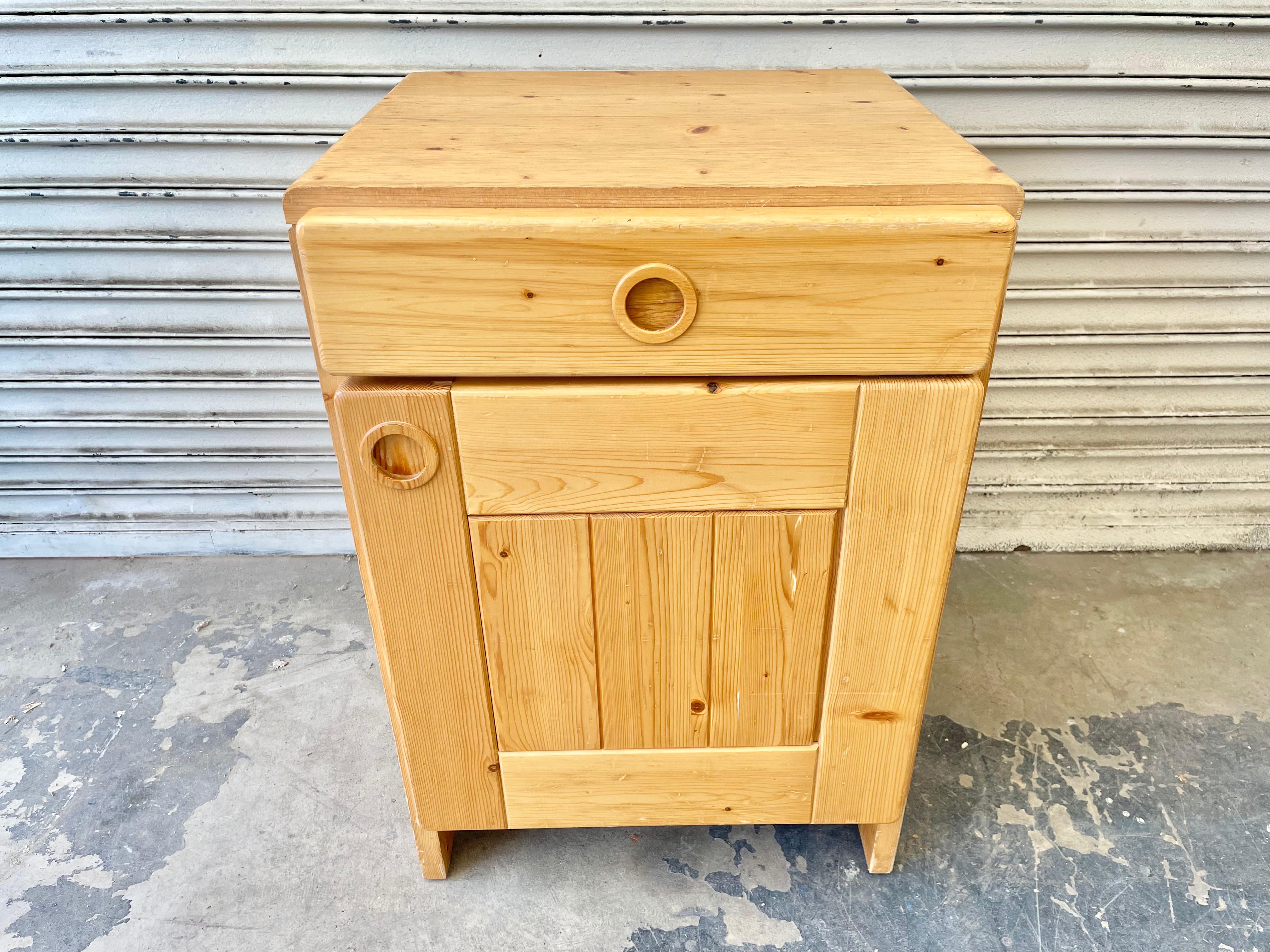 Pine bedside cupboard by Charlotte Perriand for Les Arcs. One pull out drawer. One door which opens to a shelf with two spaces for storage. Made of solid pine, circa 1960. Good original condition. Fun piece of collectible design from the popular