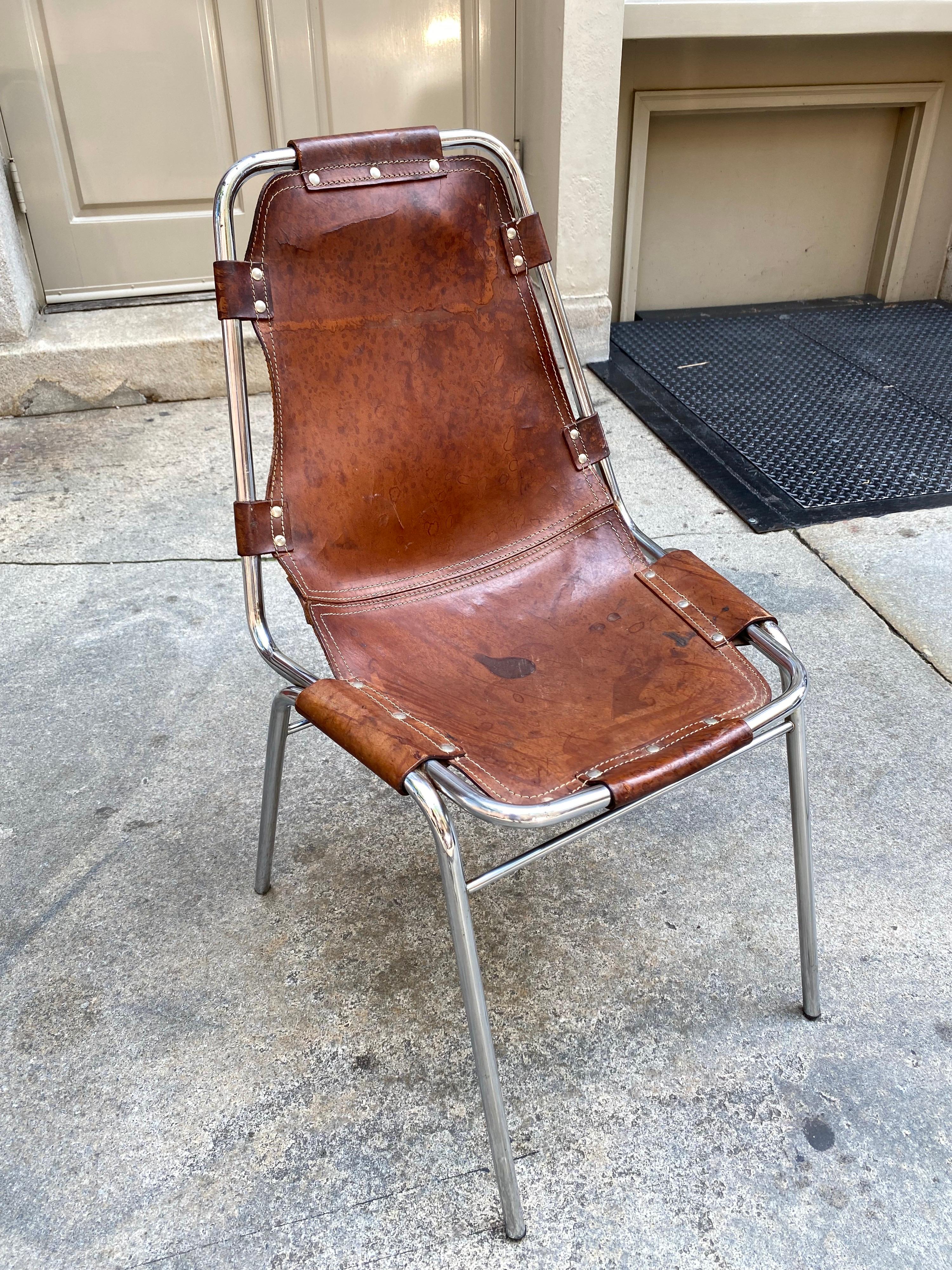 Charlotte Perriand leather and chrome chair. Heavy leather stitched and riveted around a chrome frame. This is probably a Cassina model from the 1970's. Shows loads of Patina and wear, but still solid and ready to be used or sit in that special