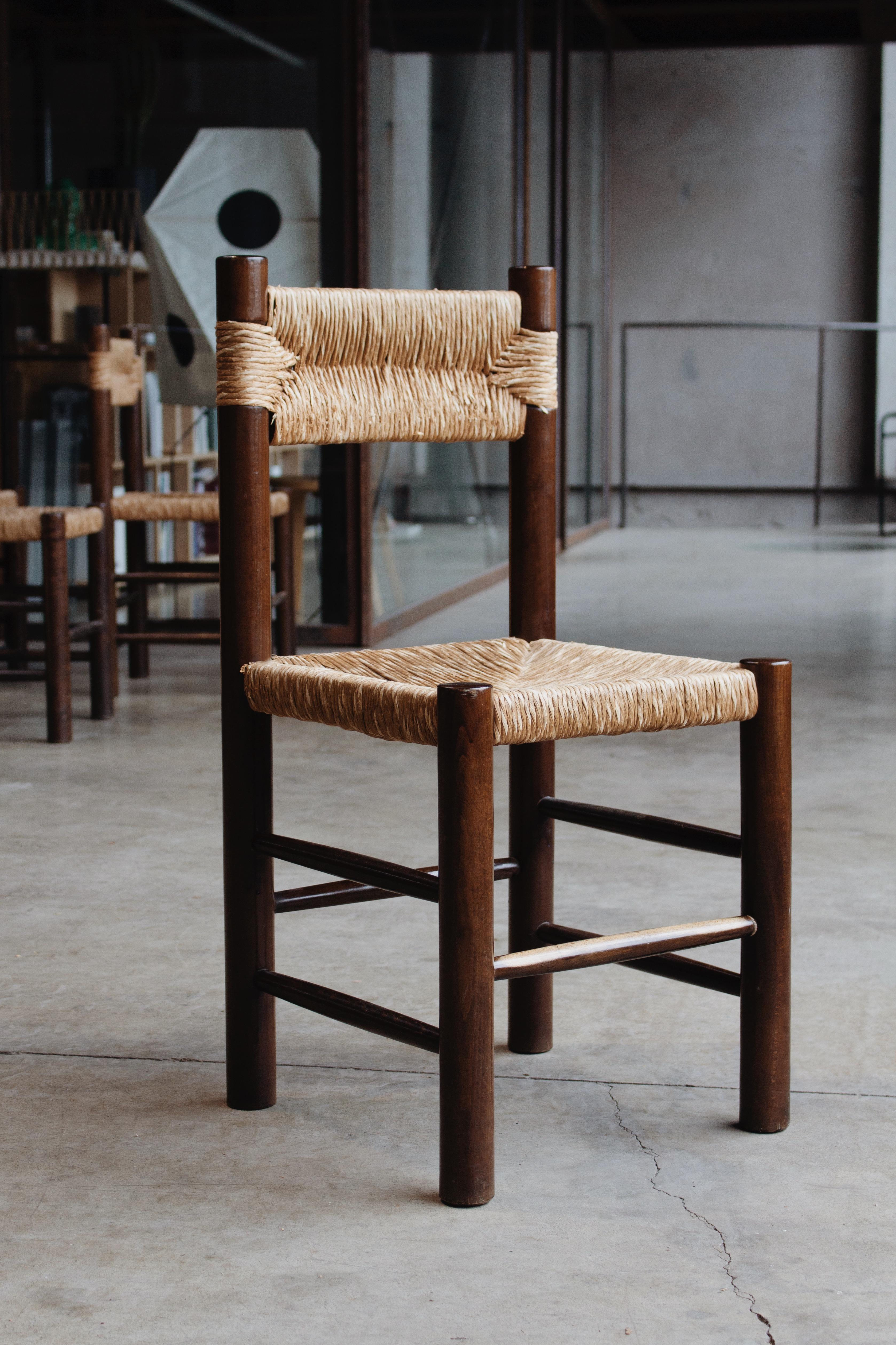 Charlotte Perriand Dining Chairs for Robert Sentou, straw and wood, France, 1964, set of four.
 
The chairs have a simple and timeless design. The fancy backrest and seat in straw combined with the pinewood structure form a truly balanced