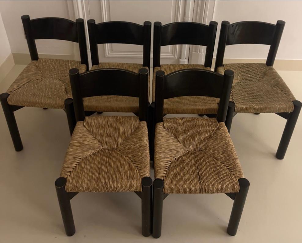 Ensemble of six chairs by Charlotte Perriand in straw and black wood.  This ensemble has a great provenance from Pierre Bergé. There is 4 higher chairs and 2 lower ones with a height difference of 3cm.