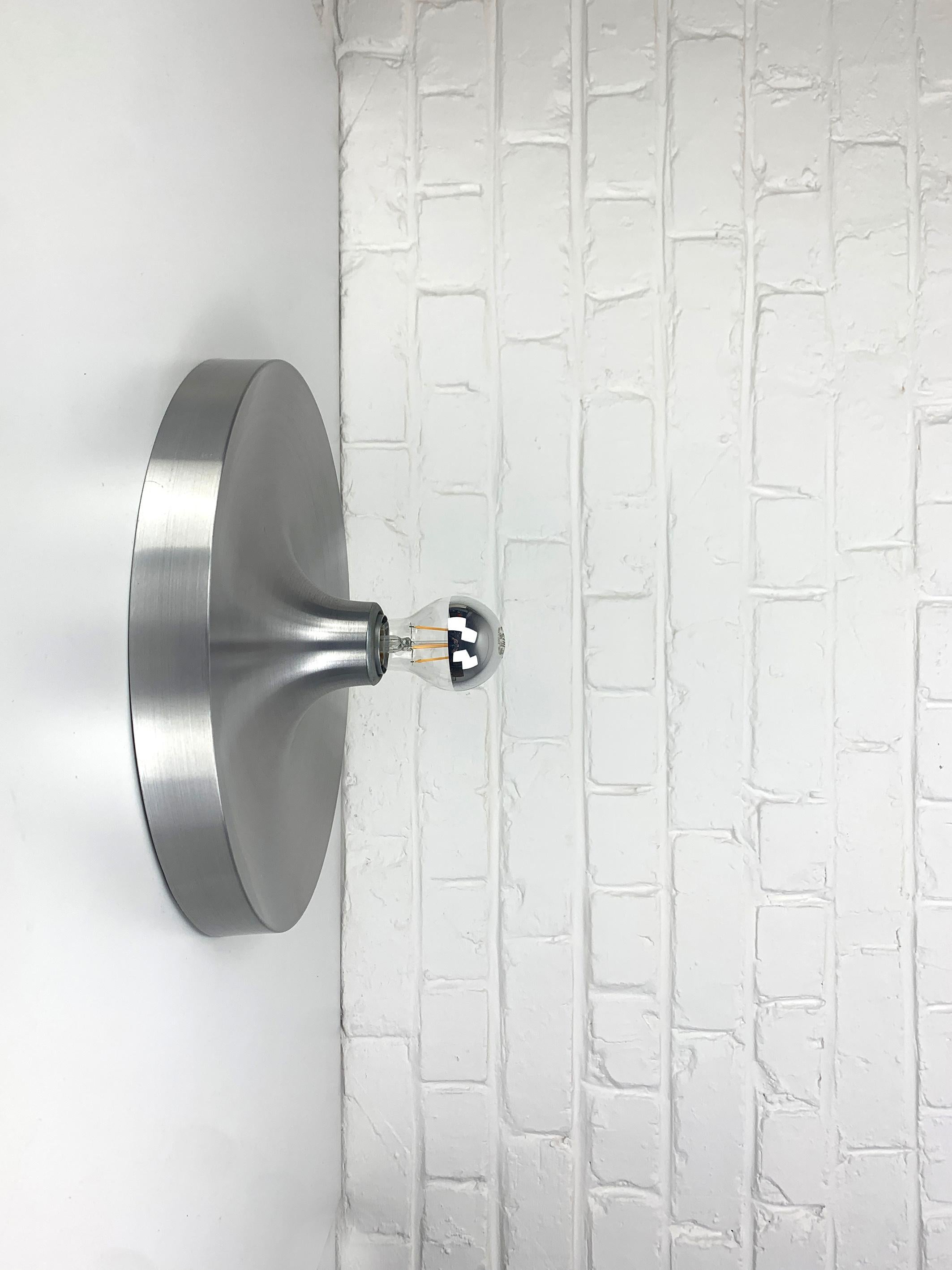 Space Age Flush wall light from the 1960s.

These sconces were commissioned / selected by Charlotte Perriand for the interior design of the flats of the 'Les Arcs' and Méribel Ski Resorts in the French Alps.

Diameter 35cm. Brushed aluminium finish.