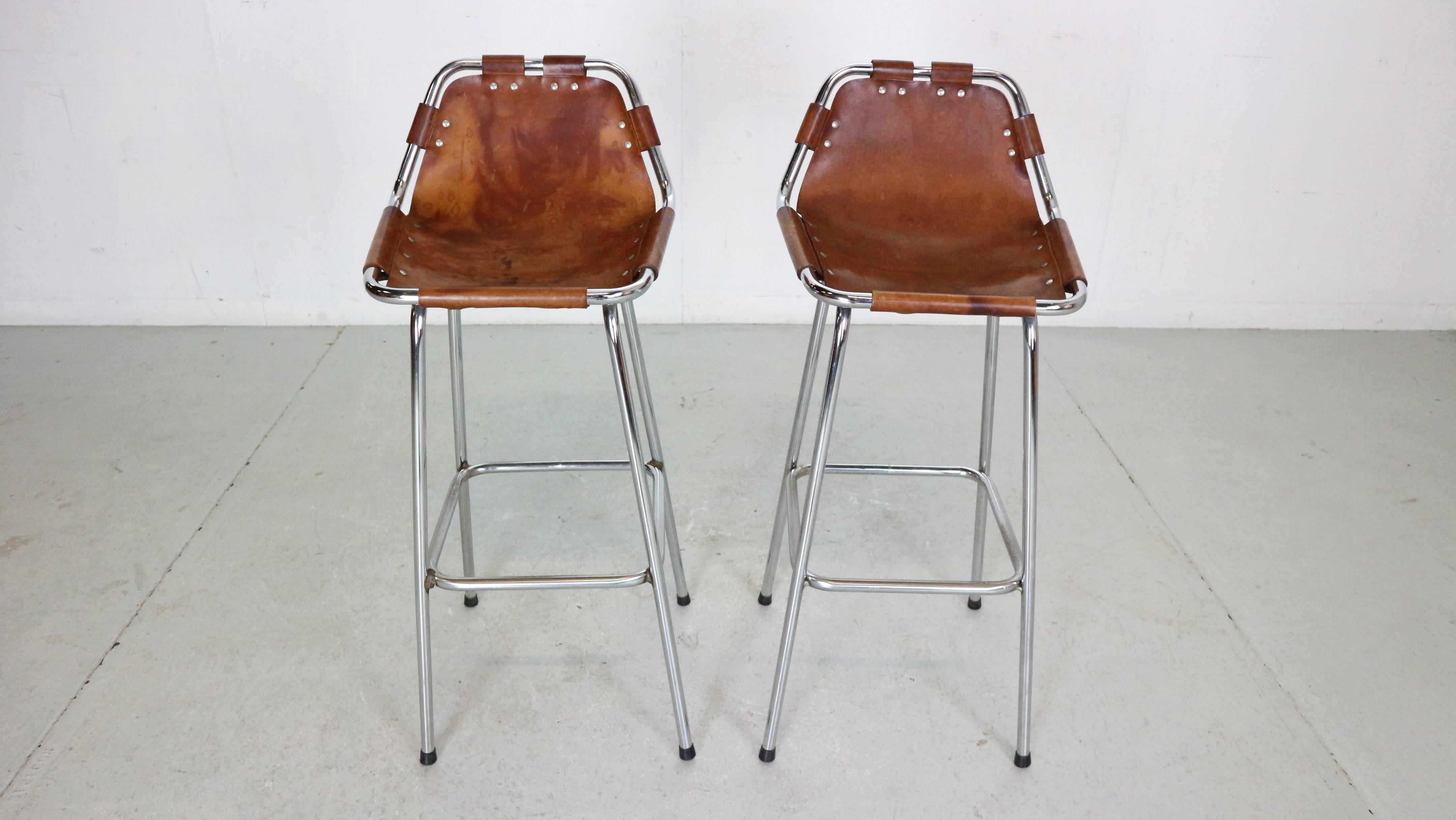 Set of 2 bar stools selected by Charlotte Perriand for the furnishing of the chalets in the luxury “Les Arcs” ski resort in France.

Charlotte Perriand was a French architect and designer. Her work aimed to create functional living spaces in the