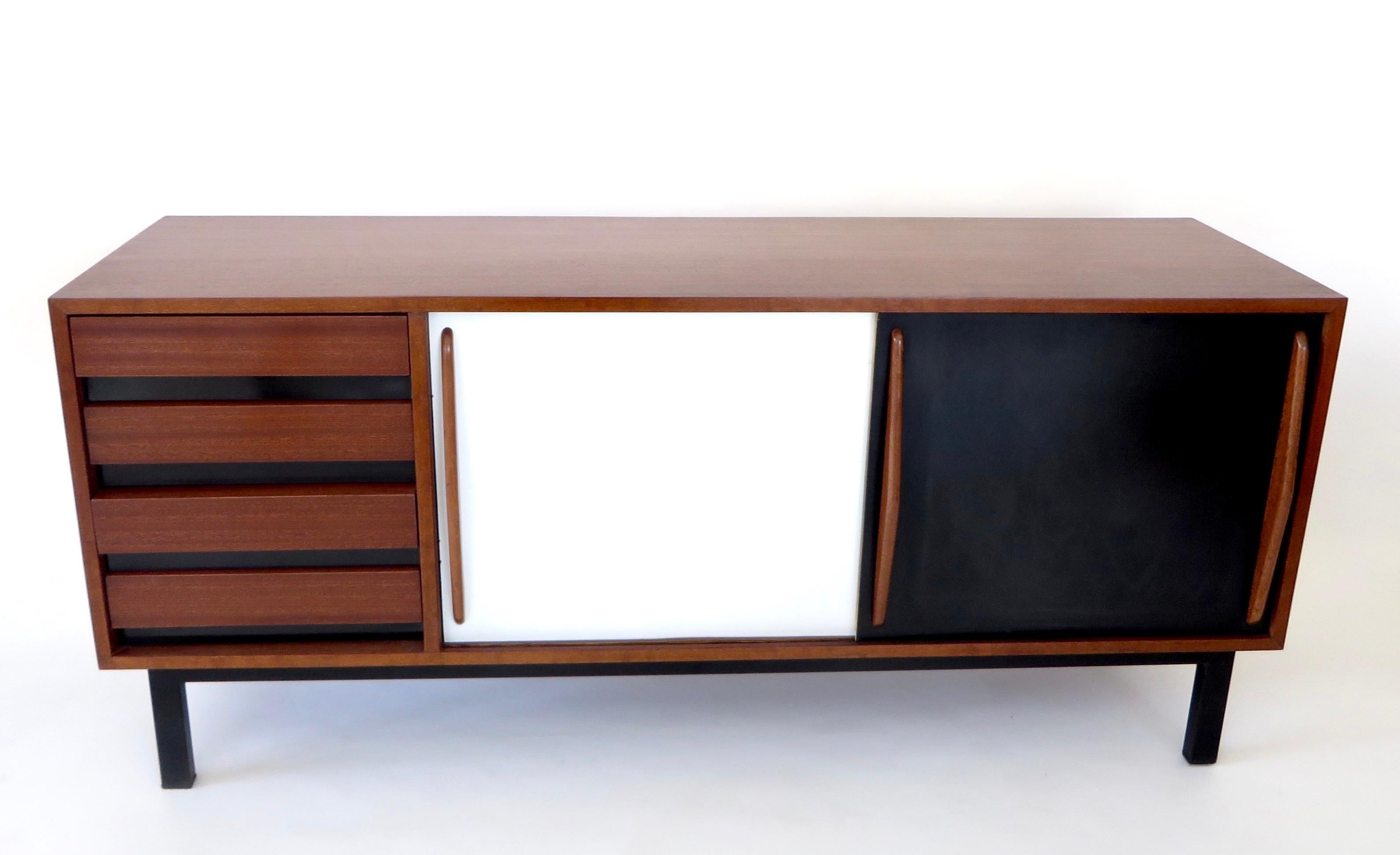 This Cansado four-drawer and sliding door sideboard was designed by Charlotte Perriand circa 1950 in the city of the same name in Mauritania. 
It has a steel base, exceptional mahagony wooden structure and grips, and lacquered laminate sliding