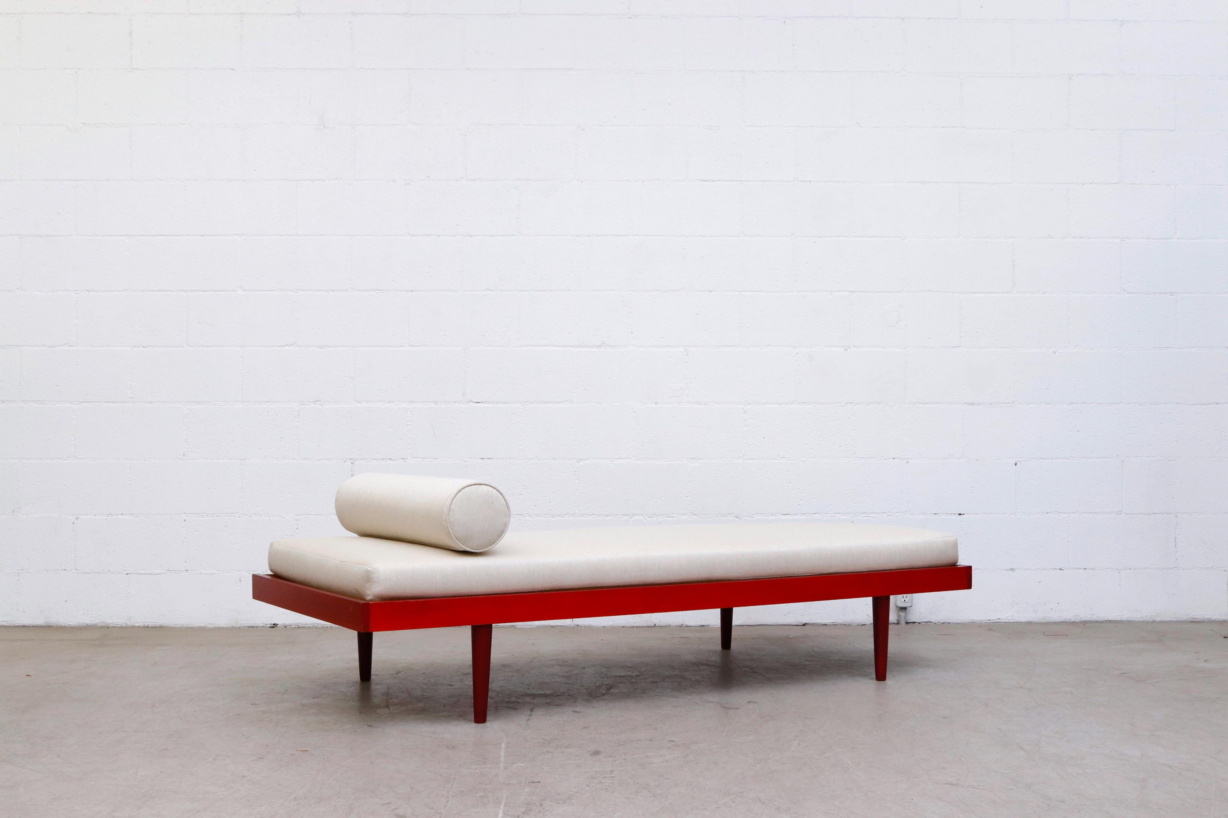 Mid-century Charlotte Perriand inspired daybed with lightly refinished red stained frame and new custom bone mattress and bolster, lightly refinished frame with tapered legs. Some visible frame wear consistent with it's age and use. Two available,