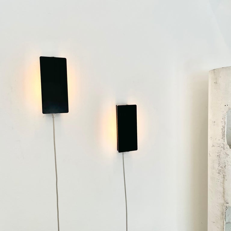 Rare large scale, enameled wall lights by Charlotte Perriand with adjustable steel reflectors in black enameled finish with two sockets each. Made in the 1960s. Optional horizontal or vertical mount. Newly rewired for US standards. 
Priced