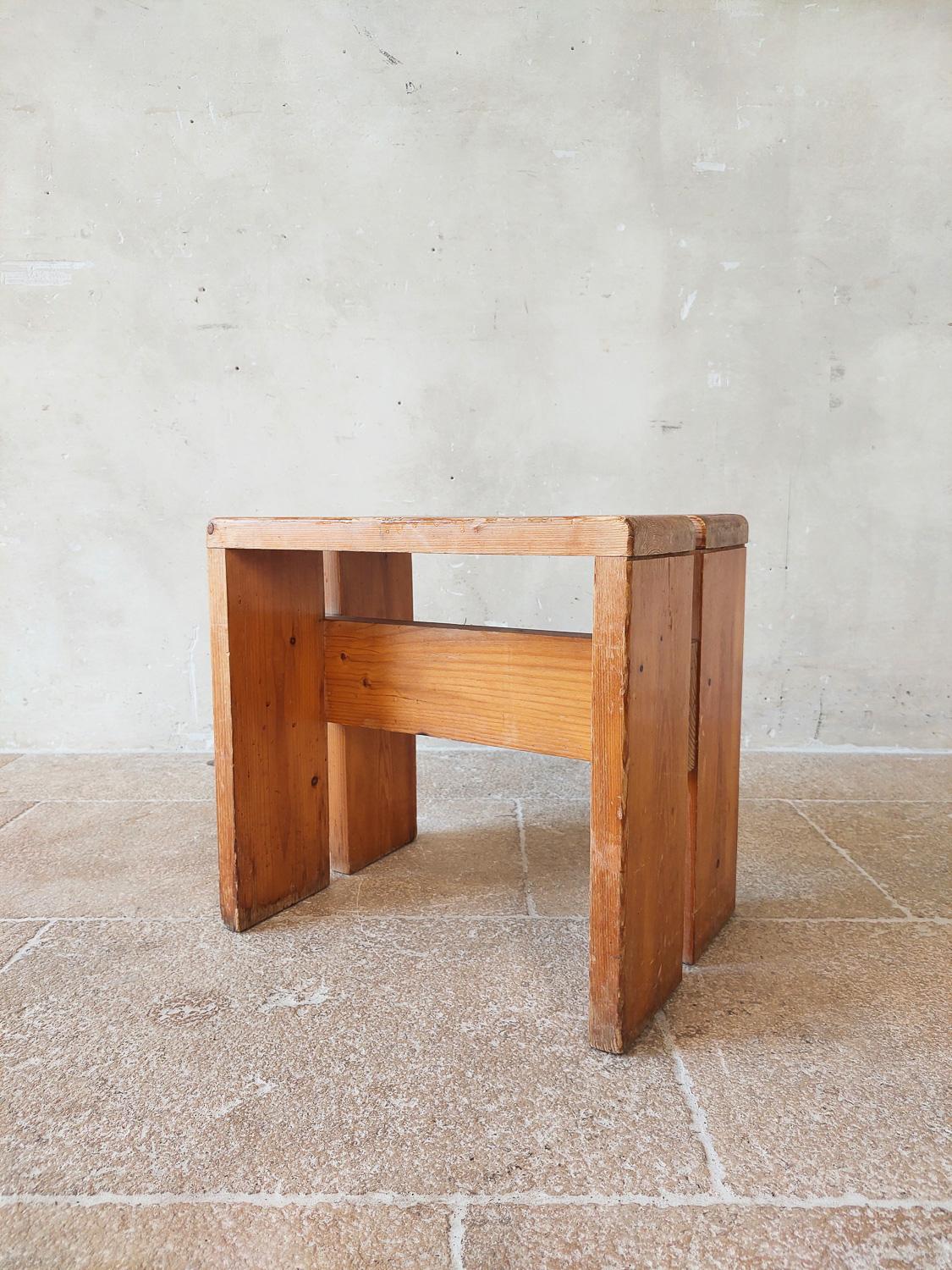Hocker, entworfen von Charlotte Perriand für den Skiort Les Arcs, um 1960, Frankreich. Dieser Hocker aus Kiefernholz ist in einem guten Zustand, mit altersgemäßen Gebrauchsspuren, aber mit einer schönen Patina.

Abmessungen: H 42,5 cm x B 45 cm x