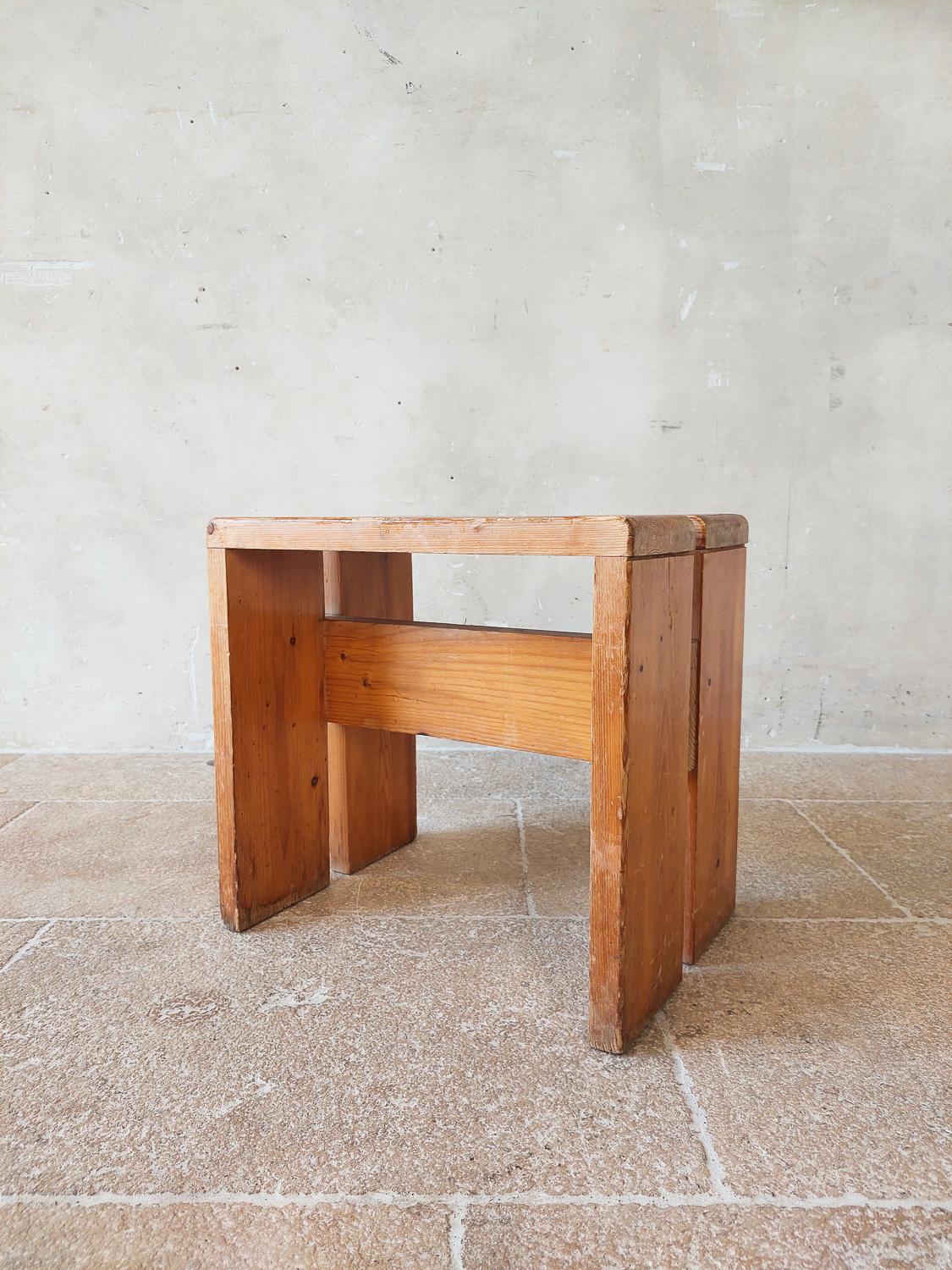 Hocker, entworfen von Charlotte Perriand für den Skiort Les Arcs, um 1960, Frankreich. Dieser Hocker aus Kiefernholz ist in einem guten Zustand, mit altersgemäßen Gebrauchsspuren, aber mit einer schönen Patina.

Abmessungen: H 42,5 cm x B 45 cm x