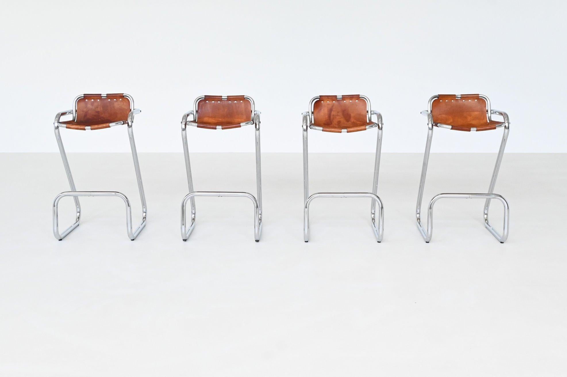 Beautiful shaped bar stools used by Charlotte Perriand for Les Arcs ski resort, France 1960. These distinctive stools feature a chromed tubular steel frame paired with original saddle leather seats and backs, displaying a rich and attractive patina
