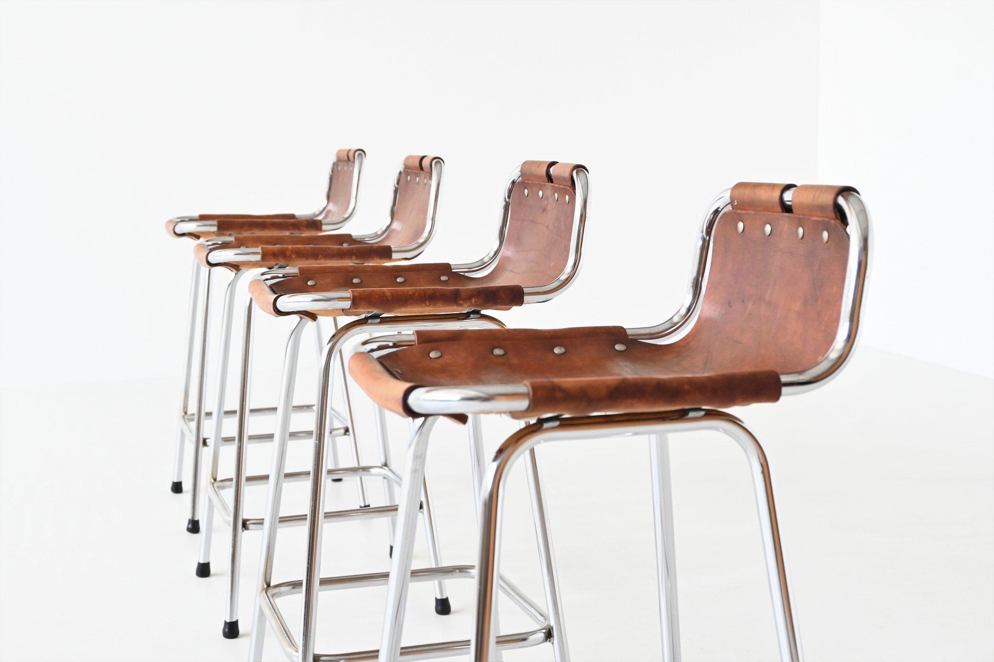 Very nice set of four beautiful shaped low bar stools used by Charlotte Perriand for Les Arcs ski resort, France 1960. The stools have chrome plated tubular metal frames and thick natural saddle leather seats with a nice patina of usage. They are