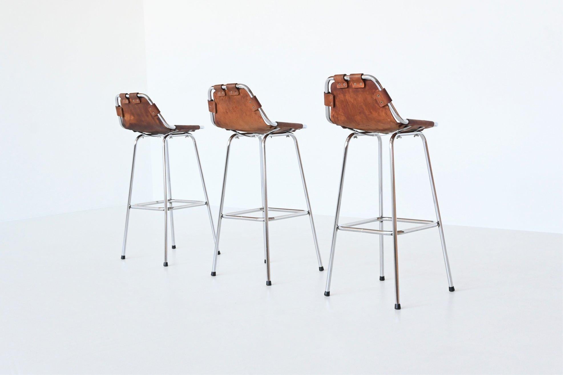 Très bel ensemble de trois tabourets de bar de belle forme utilisés par Charlotte Perriand pour la station de ski Les Arcs:: France 1960. Les tabourets ont des cadres en métal tubulaire chromé et des sièges épais en cuir de selle naturel avec une