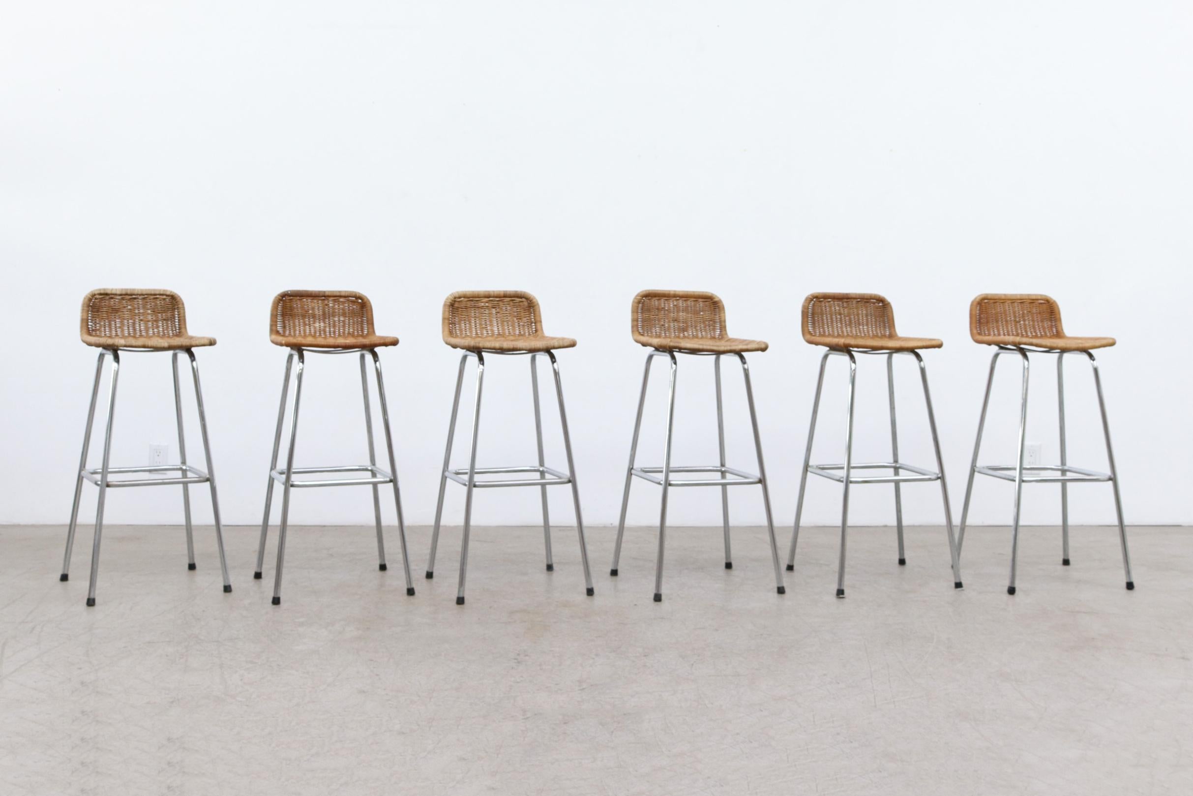 Charlotte Perriand style bar stools with low, rounded rattan seat backs and chrome tubular frames. In original condition with visible wear. Wear and rattan color varies from stool to stool. Seat Heights average 30