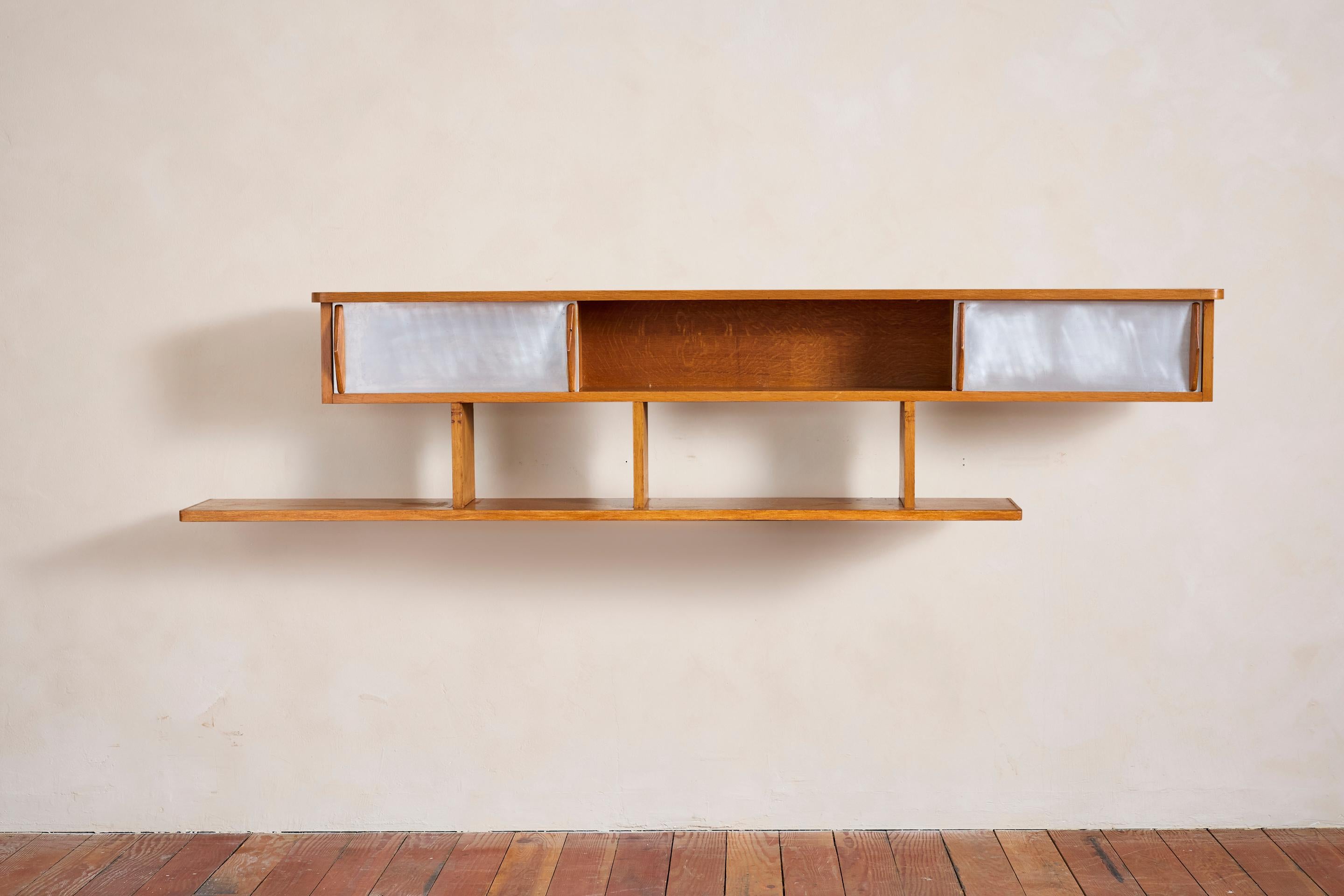 Incredible floating bookcase in the style of Charlotte Perriand with oak shelves and aluminum sliding doors. 

Oak has wonderful aged patina with radius corners and simple oak handles 

Two aluminum doors slide in both directions 

Bookcase attaches