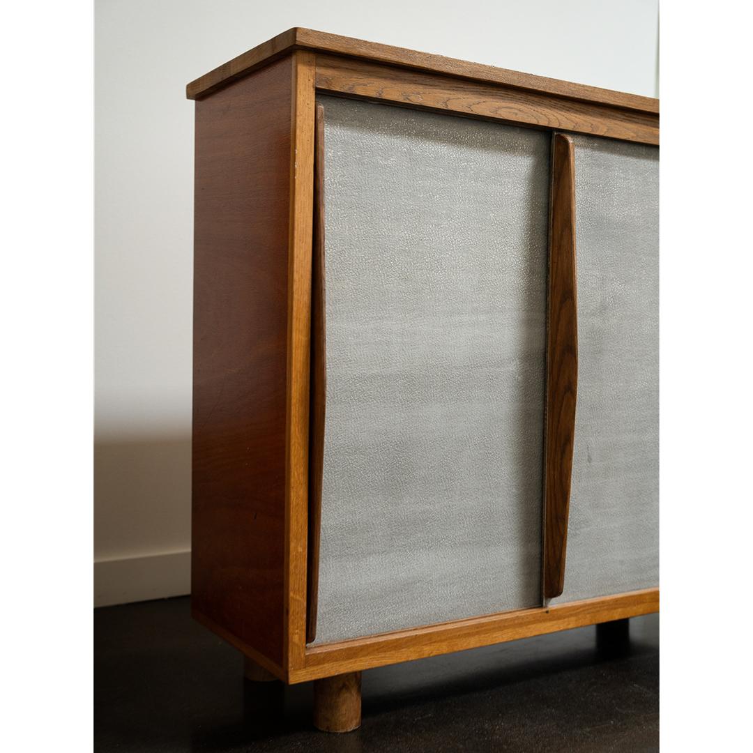 Fabriquée dans le style de Charlotte Perriand, cette armoire française combine magnifiquement des matériaux honnêtes et une forme minimaliste. Le cadre en chêne massif apporte chaleur et structure, tandis que les portes coulissantes en aluminium