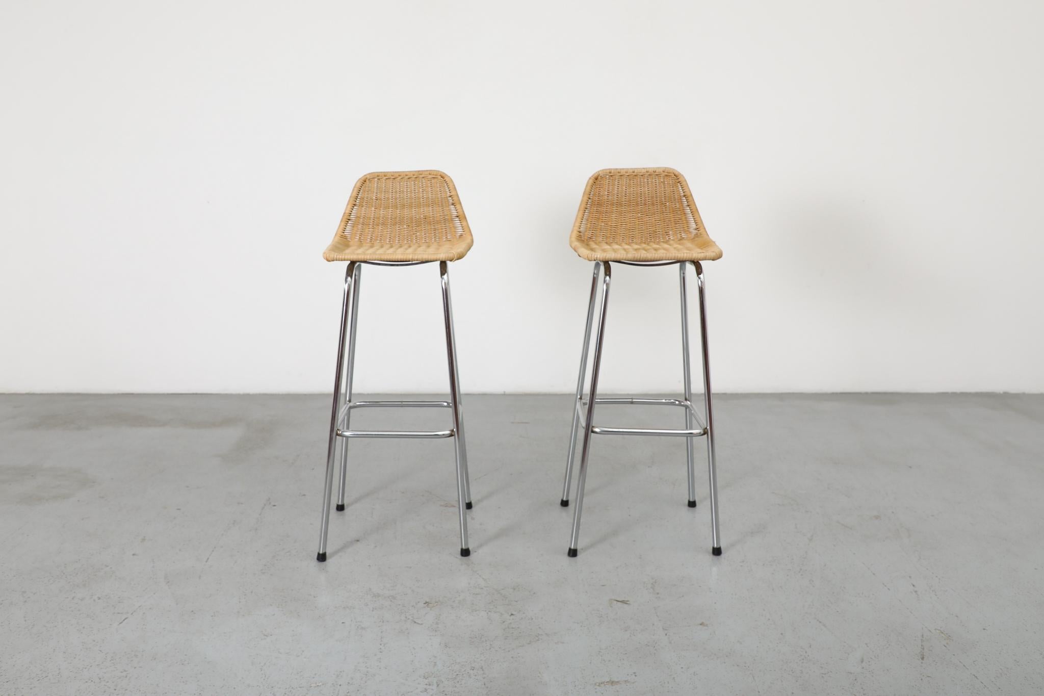 Charlotte Perriand inspired wicker and chrome bar stools with angled seat back. Light and stylish bar stools with plastic cap feet perfect for a cozy dining area or a covered outdoor space. In original condition with some wear consistent with age