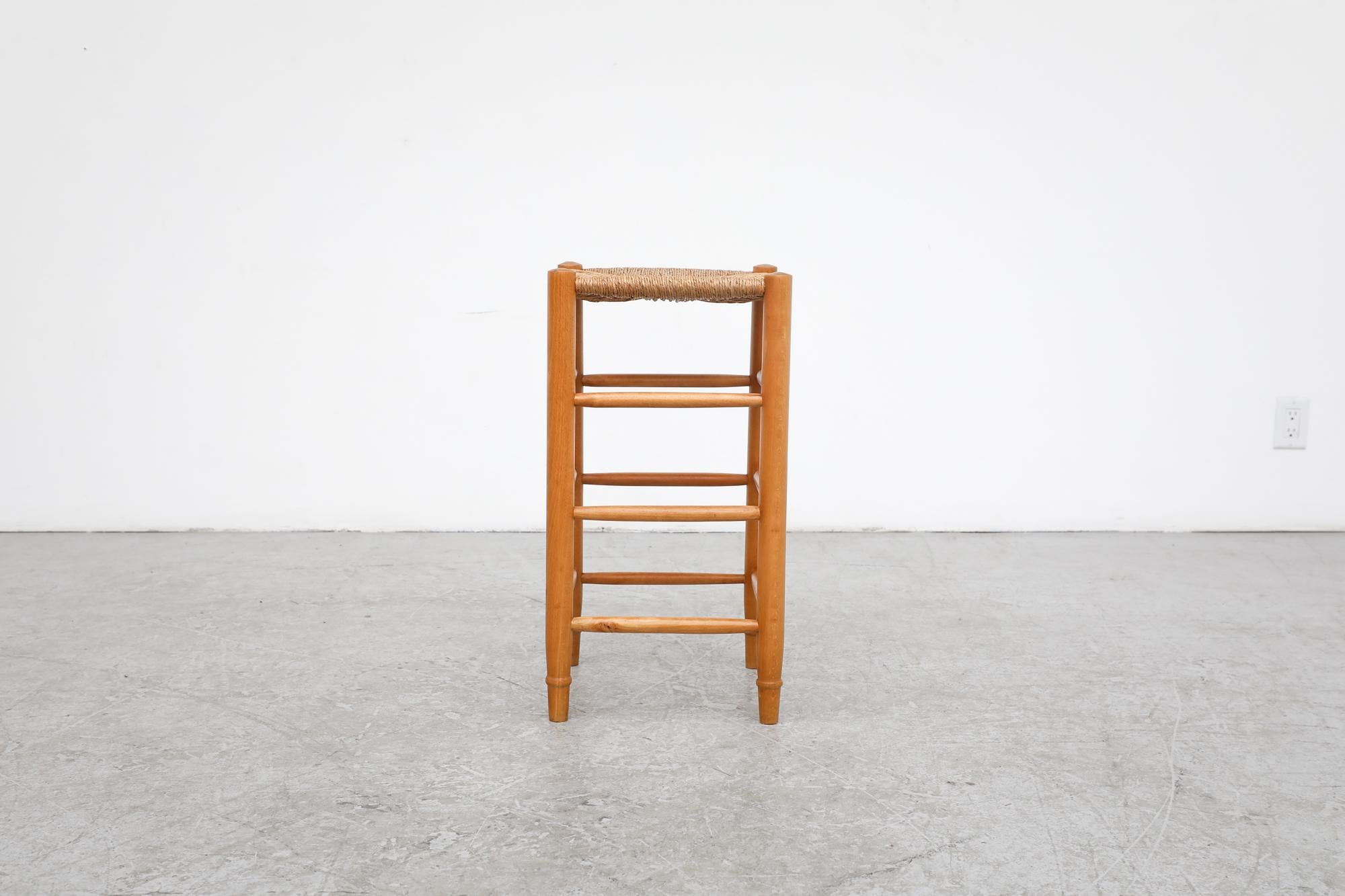 Charlotte Perriand style counter height stool with woven rush seat and oak frame. In original condition with visible wear and may be have rush breakage. Wear is consistent with its age and use. Other similar stools available and listed separately.