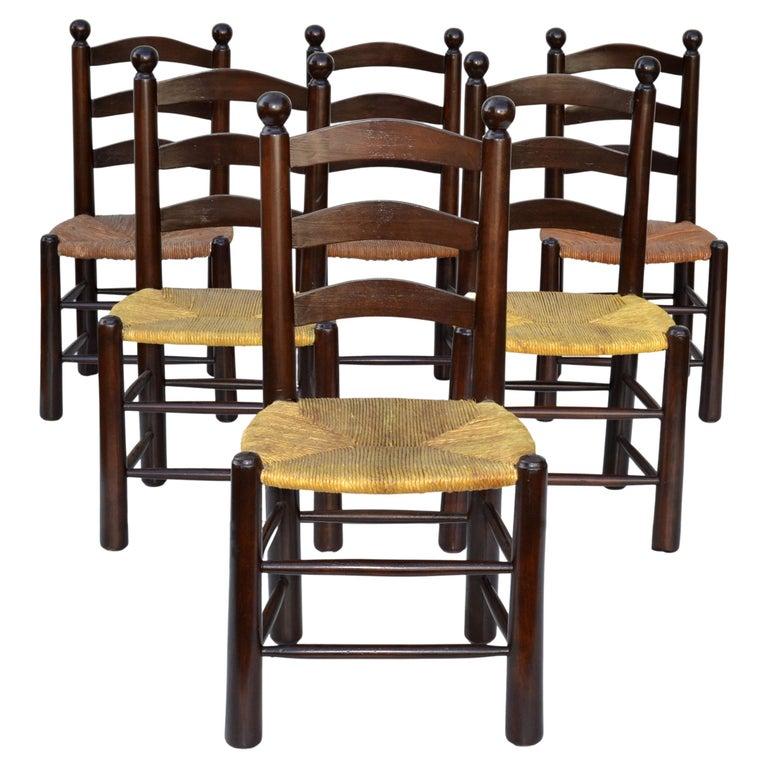 Very rare set of six dining chairs in the manner of Charlotte Perriand.
Turned oak wood core with the handwoven rush seats which are in perfect original condition.
The wood has been restored in a dark brown Finish. 
The Set of 6 Chairs are ready