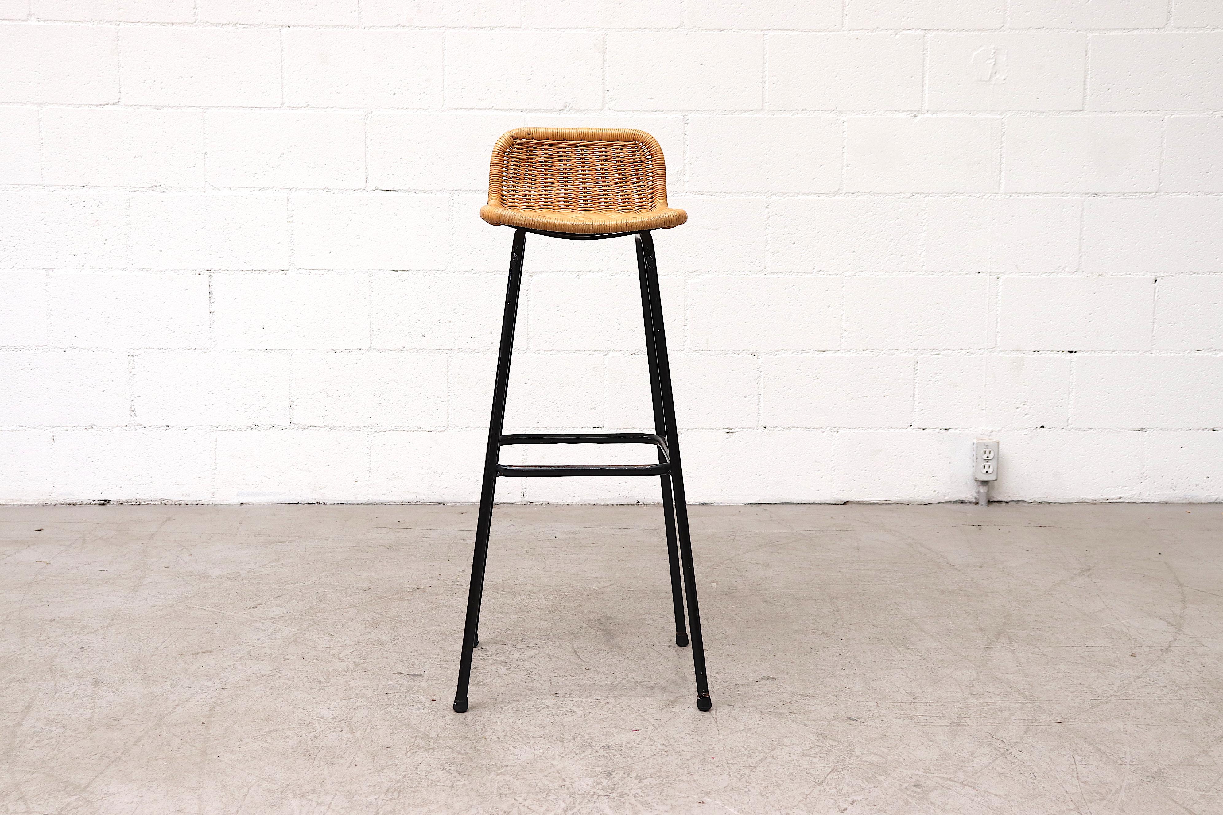 Charlotte Perriand style bar stool with low square rattan seat back on black enameled tubular metal frame in original condition with visible patina, may have some enamel and/or rattan loss. 36