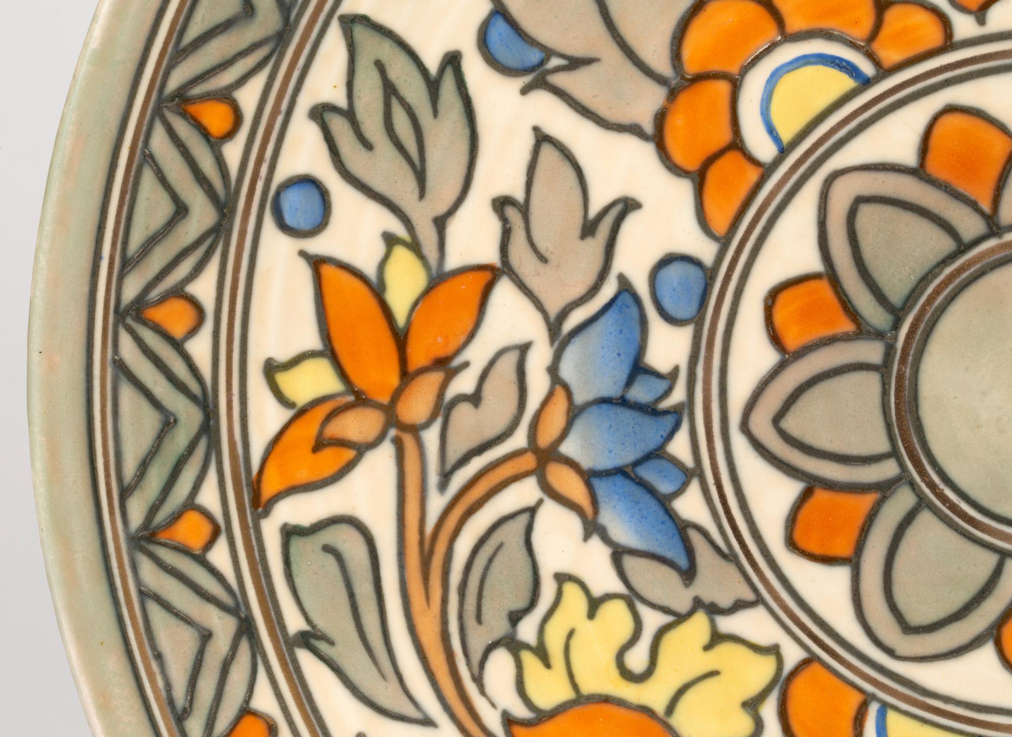 Un élégant chargeur décoratif en poterie tubulaire Art Déco de Crown Ducal, décoré de motifs floraux par Charlotte Rhead et datant du début des années 1930. Le chargeur est de forme arrondie, avec un motif floral central inséré dans une large bande