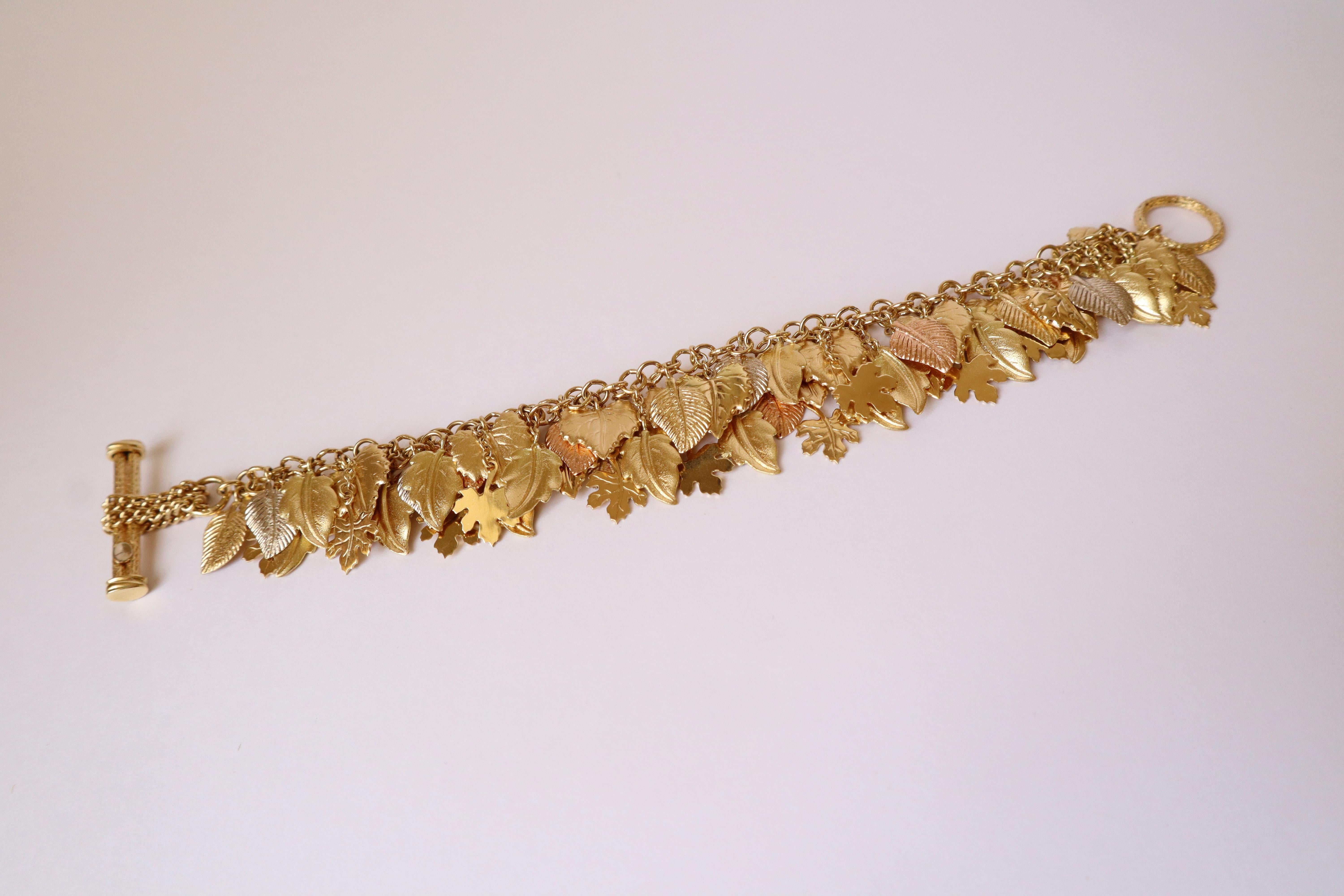 Armband Charm 3 Gold 18 Karat mit Blattmuster
Doppelkette aus Gelbgold, die verschiedene Arten von Baumblättern in verschiedenen Goldfarben (weiß, rosa und gelb) mit 18 Karat hält. Goldpunze: Eule. 
Länge: 19 cm Breite: 4 cm 
Nettogewicht: 54 g