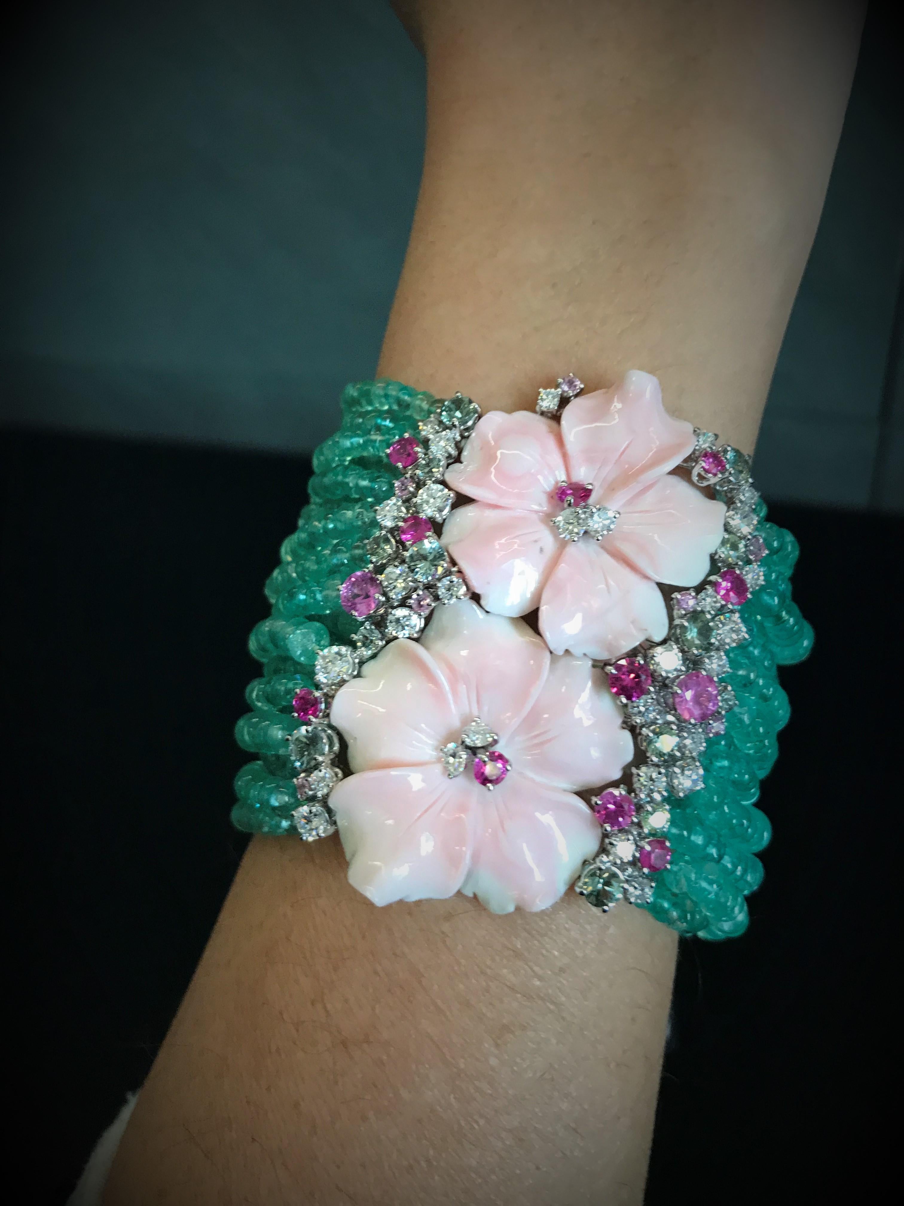 This bracelet, inspired by the fresh sweetness of flowers is made in white gold, emeralds beads threads, pink shell flowers, round brilliant cut diamonds, pink and green sapphires. 
Diamonds total ct 2.66
Emeralds total ct 394.85
Sapphires total ct