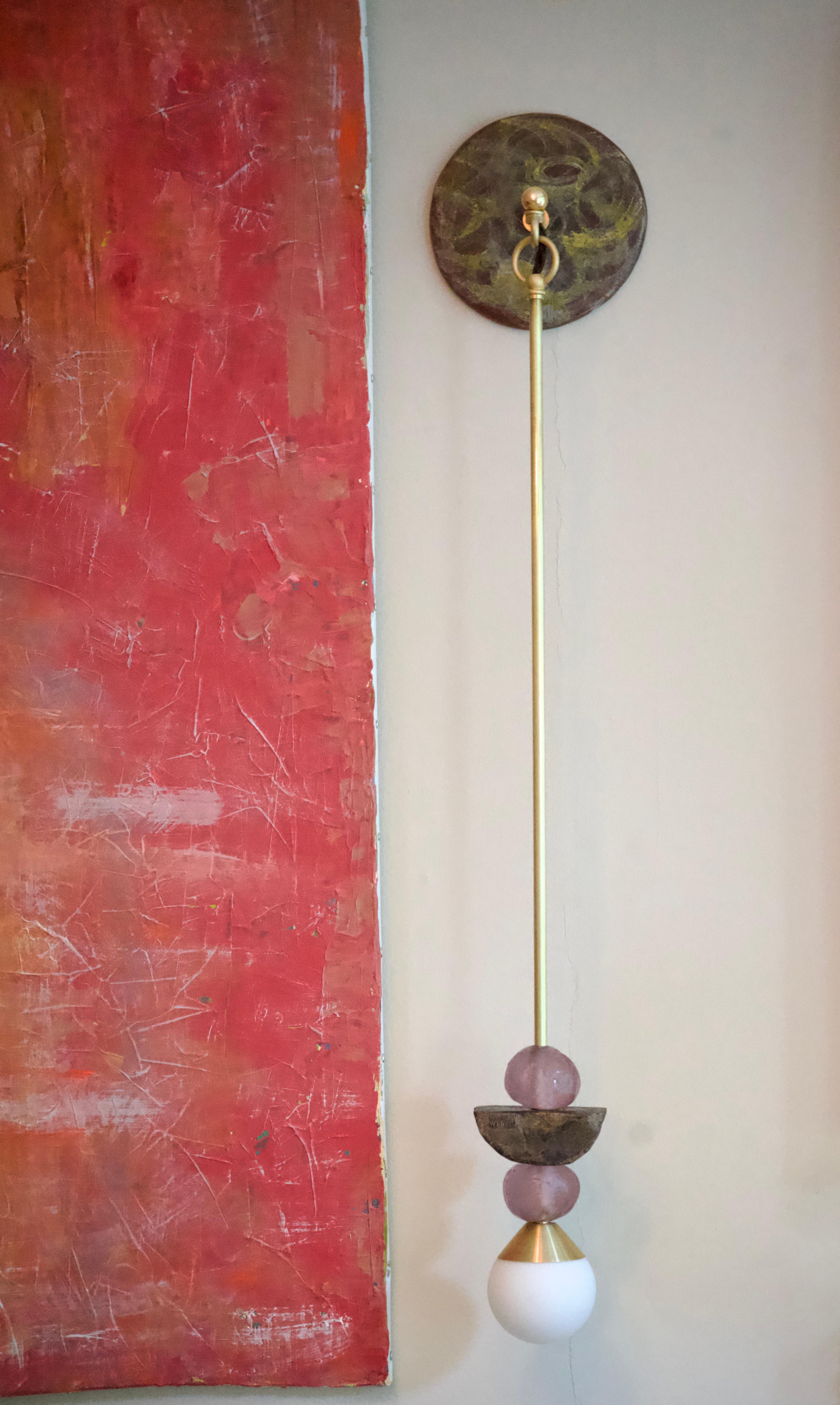 The 'Charm' wall light with amethyst and bronze-patina hand-sculpted components is cast in Margit Wittig's London-based studio.
The abstract finish on the wall plate enhances the organic surface texture, a brass detail adds interest to this object