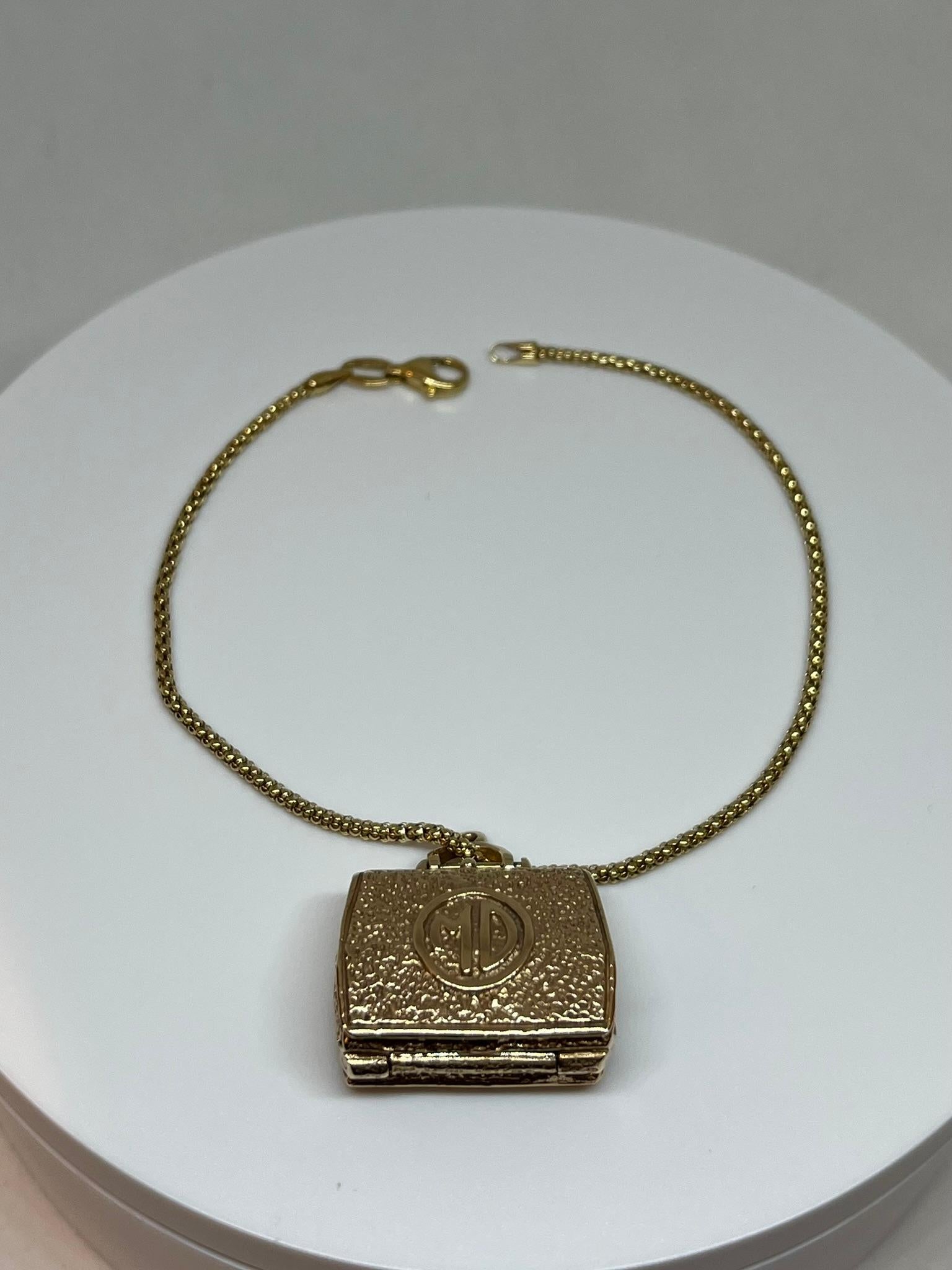 Este amuleto vintage de oro de 14 quilates es único en su especie, ya que contiene una increíble variedad de detalles, con gran atención al detalle y un realismo loco. El maletín del médico, cuando está cerrado, está trabajado de tal forma que