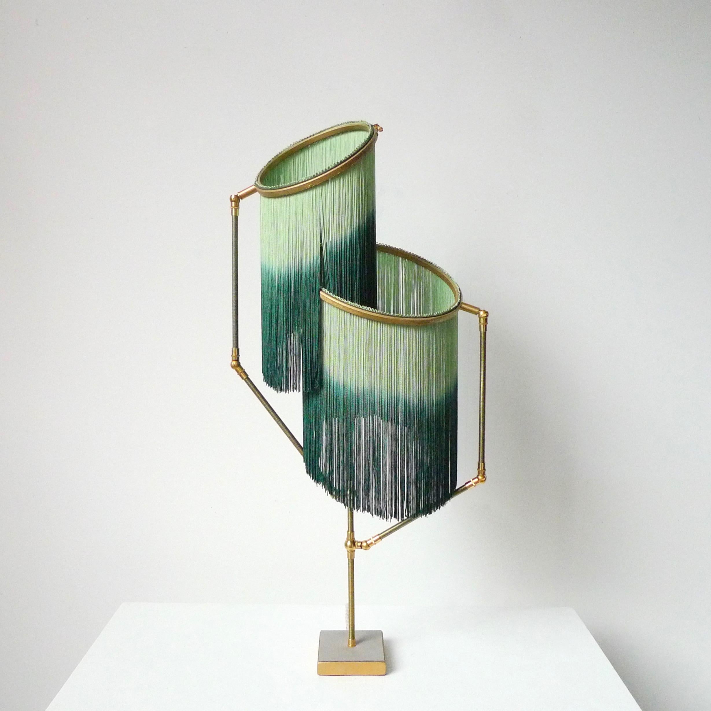Charme Table Lamp by Sander Bottinga

Dimensions: H 73 x W 38 x D 25 cm
Hand-sculpted in brass, leather, wood and dip dyed colored Fringes in viscose.
The movable arms makes it possible to move the circles with fringes in differed positions.
So