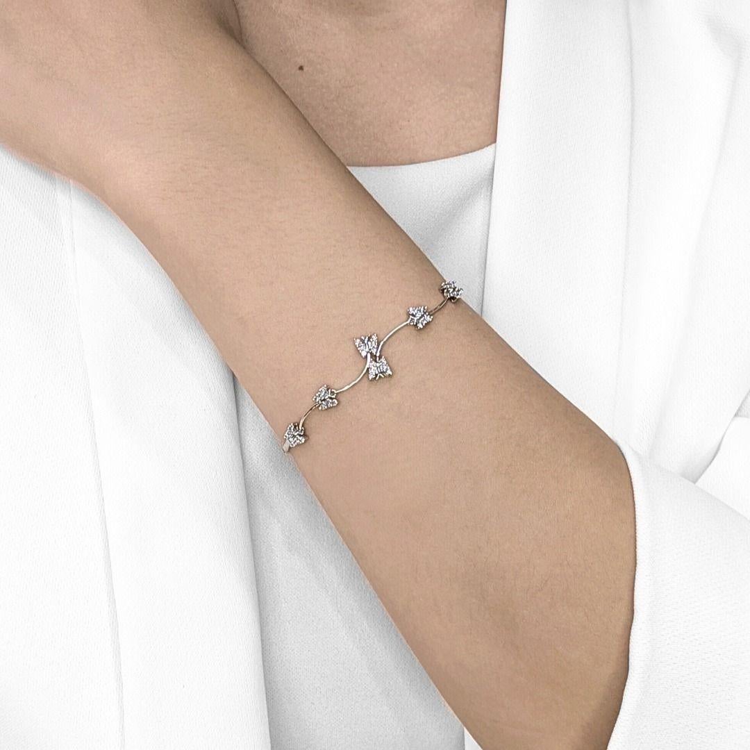 Embrace playful elegance with this new, unworn bracelet, meticulously crafted in radiant 18K white gold. This enchanting piece features a delicate, flowing design adorned with five charming butterfly motifs, each sparkling with brilliant natural
