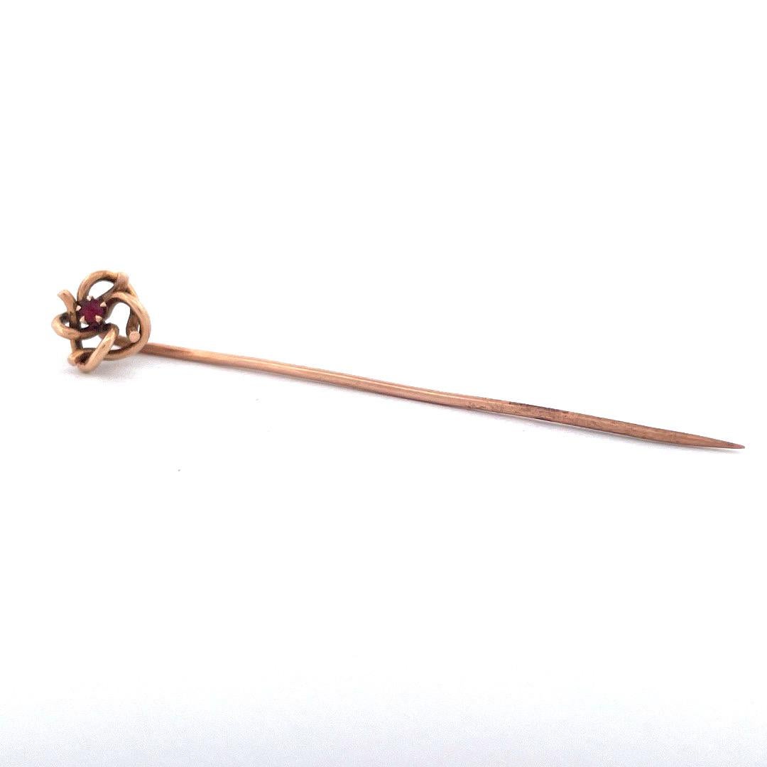 Add a touch of charm with this 14k yellow gold ruby knot pin. The pin features an intricate knot design,  with a captivating ruby at its center. Crafted with delicate precision, this pin weighs 1.2 grams, offering a lightweight and comfortable