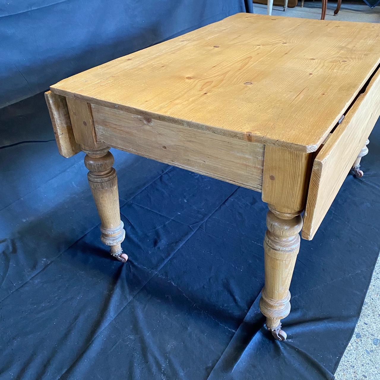 Lovely 19th century country English farmhouse dining table or harvest table with original casters, finely turned legs and drop leaves on each side. The tops are crafted thick pine boards with a lovely warm pine color and natural finish. Supported by