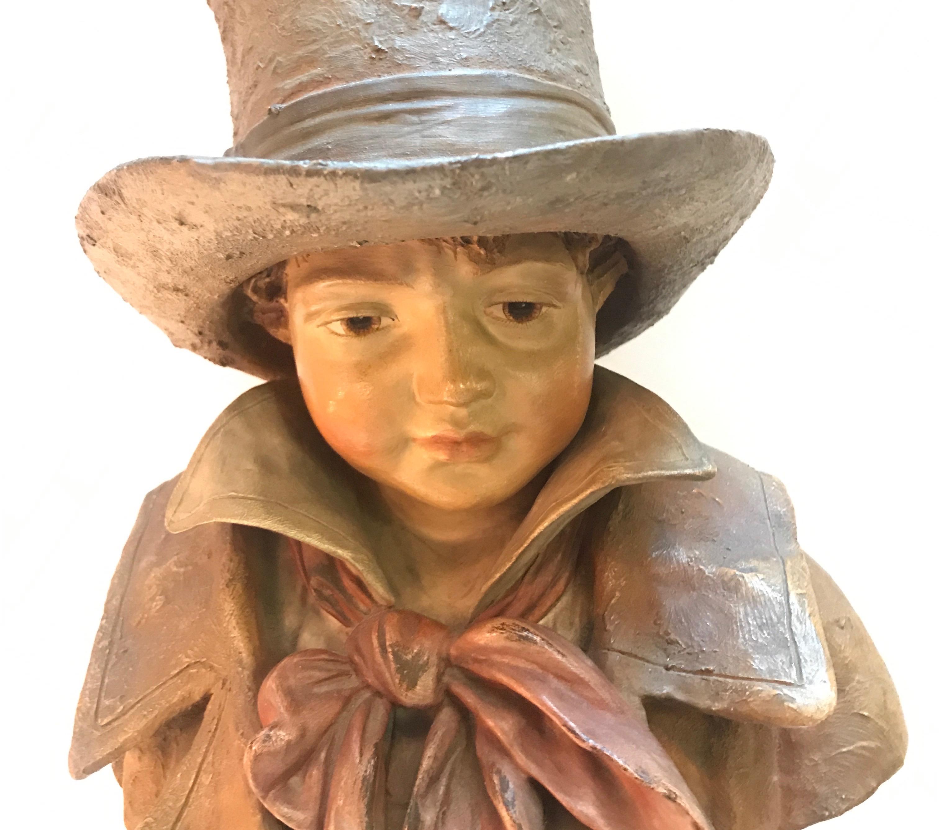 Beautifully painted terracotta bust of a young aristocratic boy in top hat. Nicely detailed clothing and face with a pedestal shaped base.
 