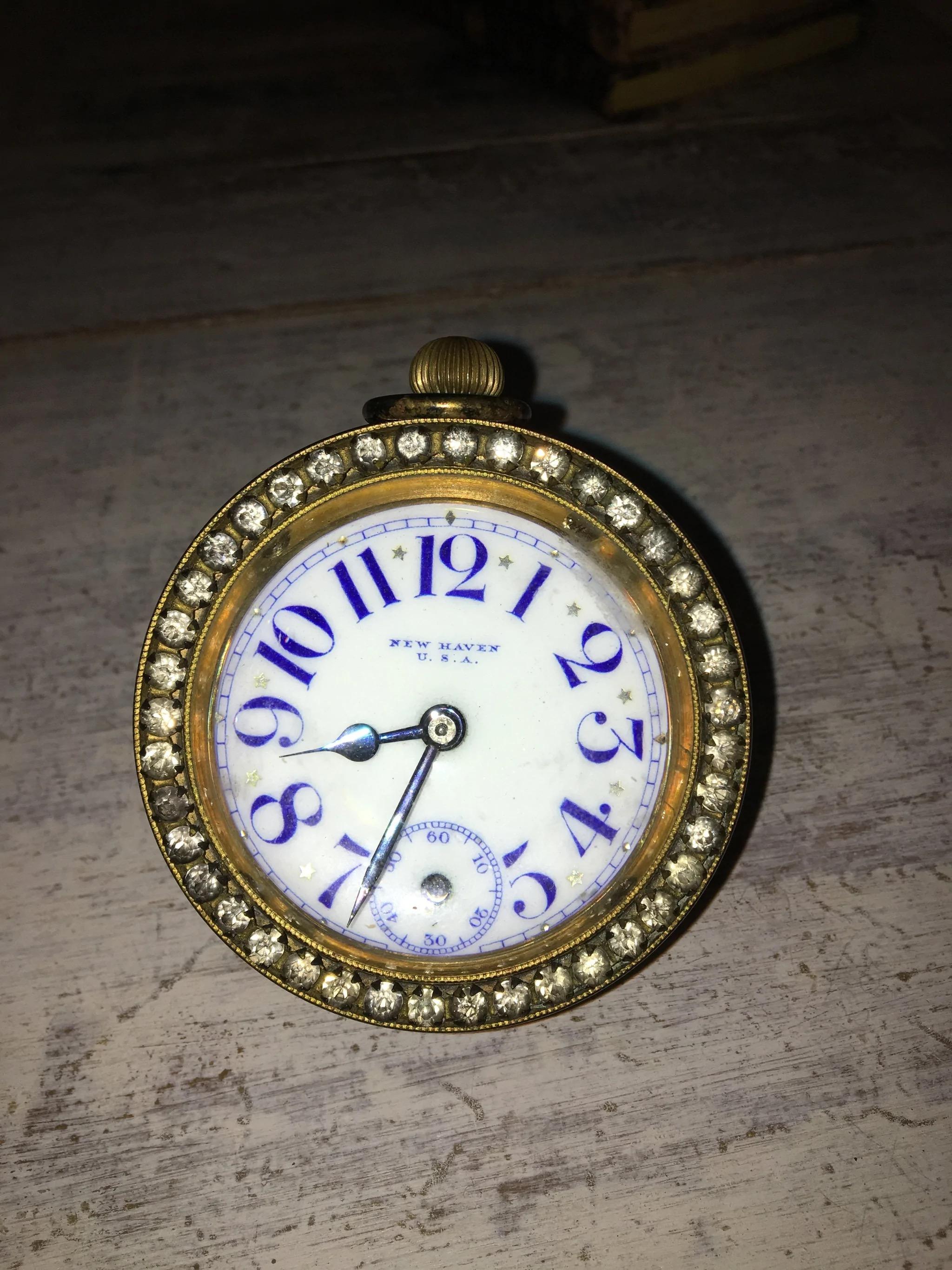 This is a beautiful American-made jeweled ball clock. In working condition, though missing its second hand. Bold blue numerals on an enamel face, brass and paste diamonds surround. Also known as a paperweight clock.
  