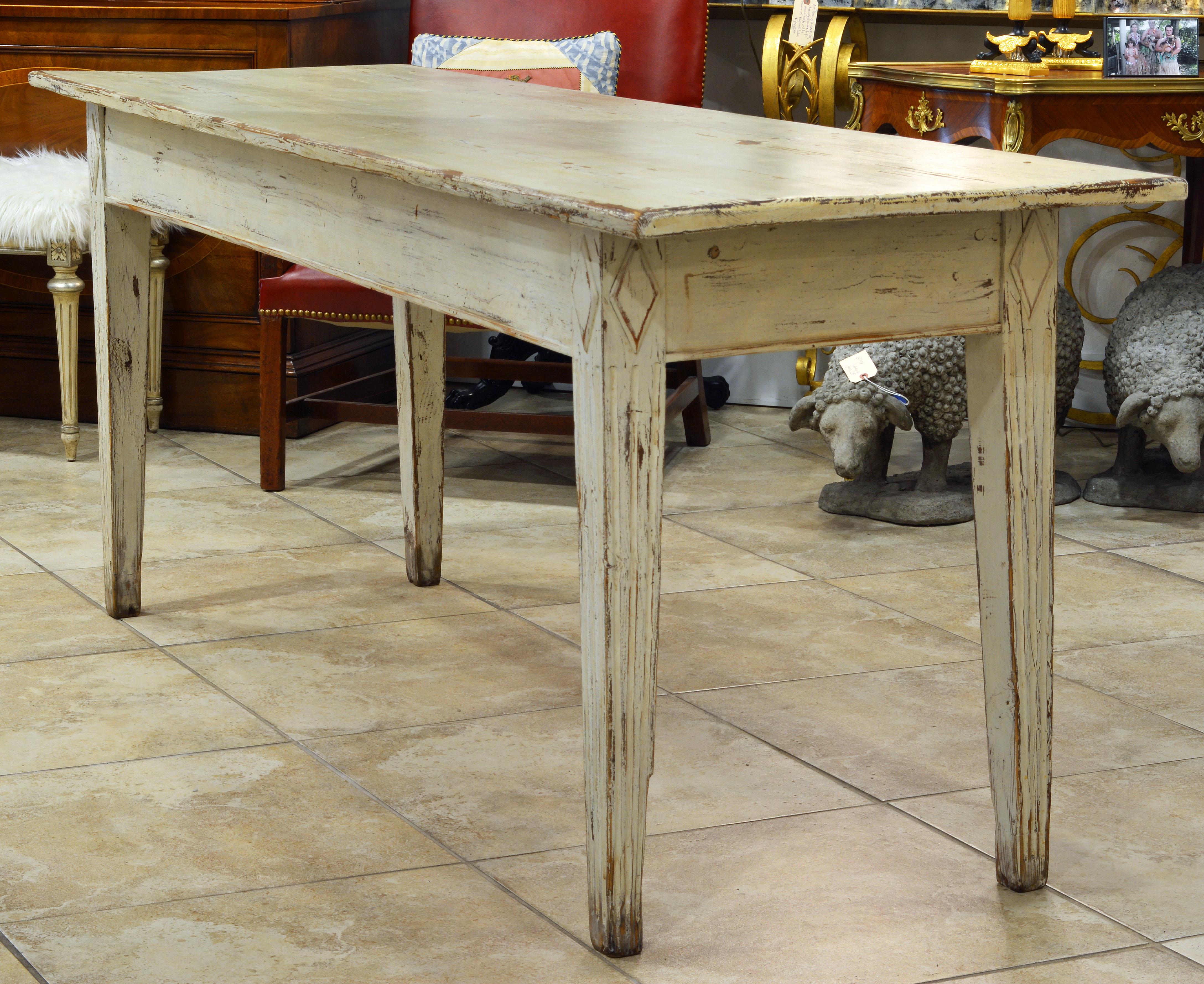 This 19th century Gustavian style farm table has a fetching look with a beautifully worn paint layer and fluted tapering legs surmounted by carved diamond reliefs. Sometimes less is more, and the charming simplicity of this table will compliment any