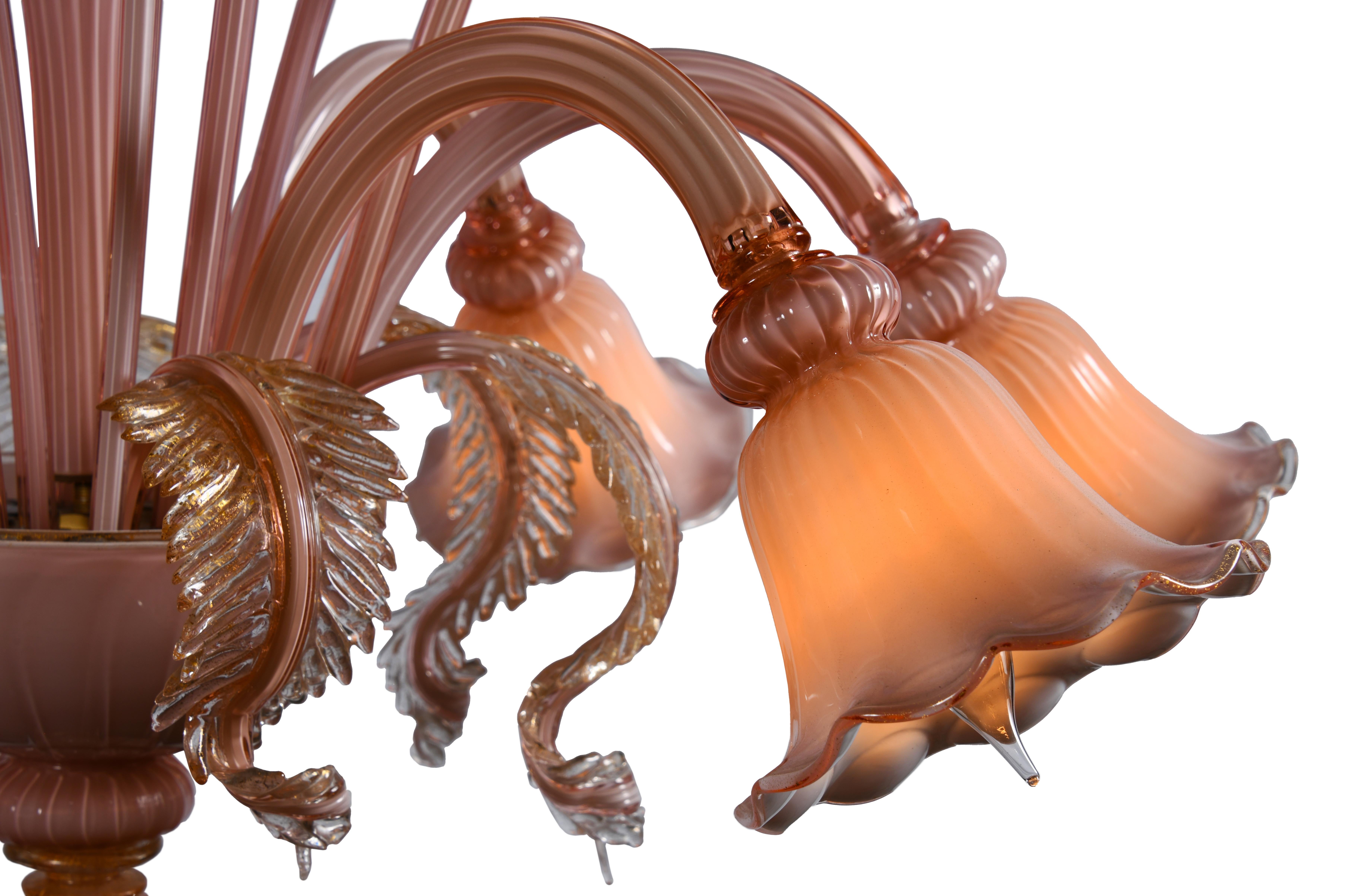 Un delizioso lampadario a sospensione nel classico stile di Murano con corpo e bracci in vetro rosa scanalato, accenti di fiori e foglie realizzati a mano in cristalo d'oro trasparente con oro a 24 carati.

Lo Studio Thomas Cooper rappresenta una