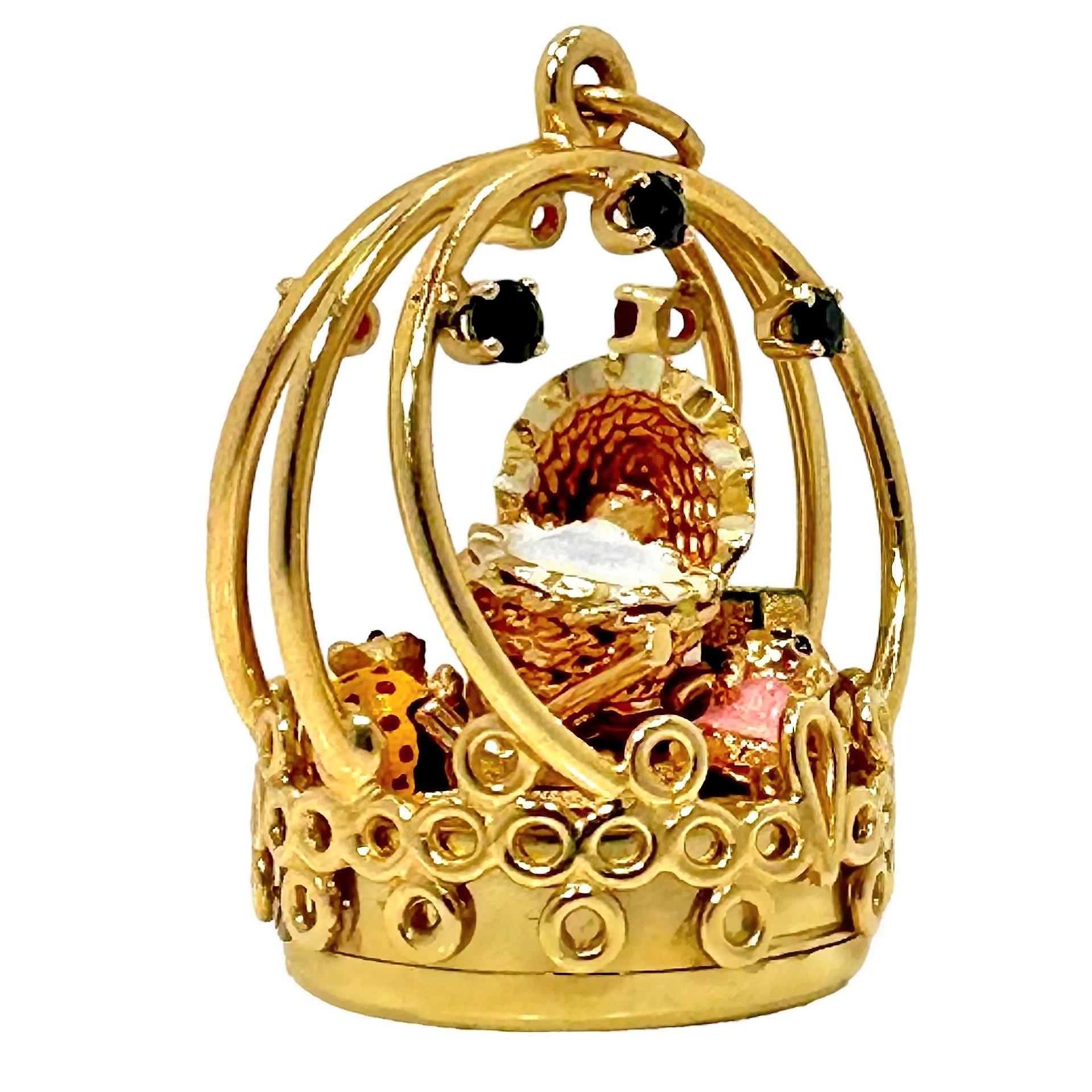 This imaginative and whimsical  pendant features a small infant in covered stroller under a golden arch accented with rubies and sapphires. Multicolored hot enamel accents highlight eyes, mouth and blanket as well as the child's teddy bear, building