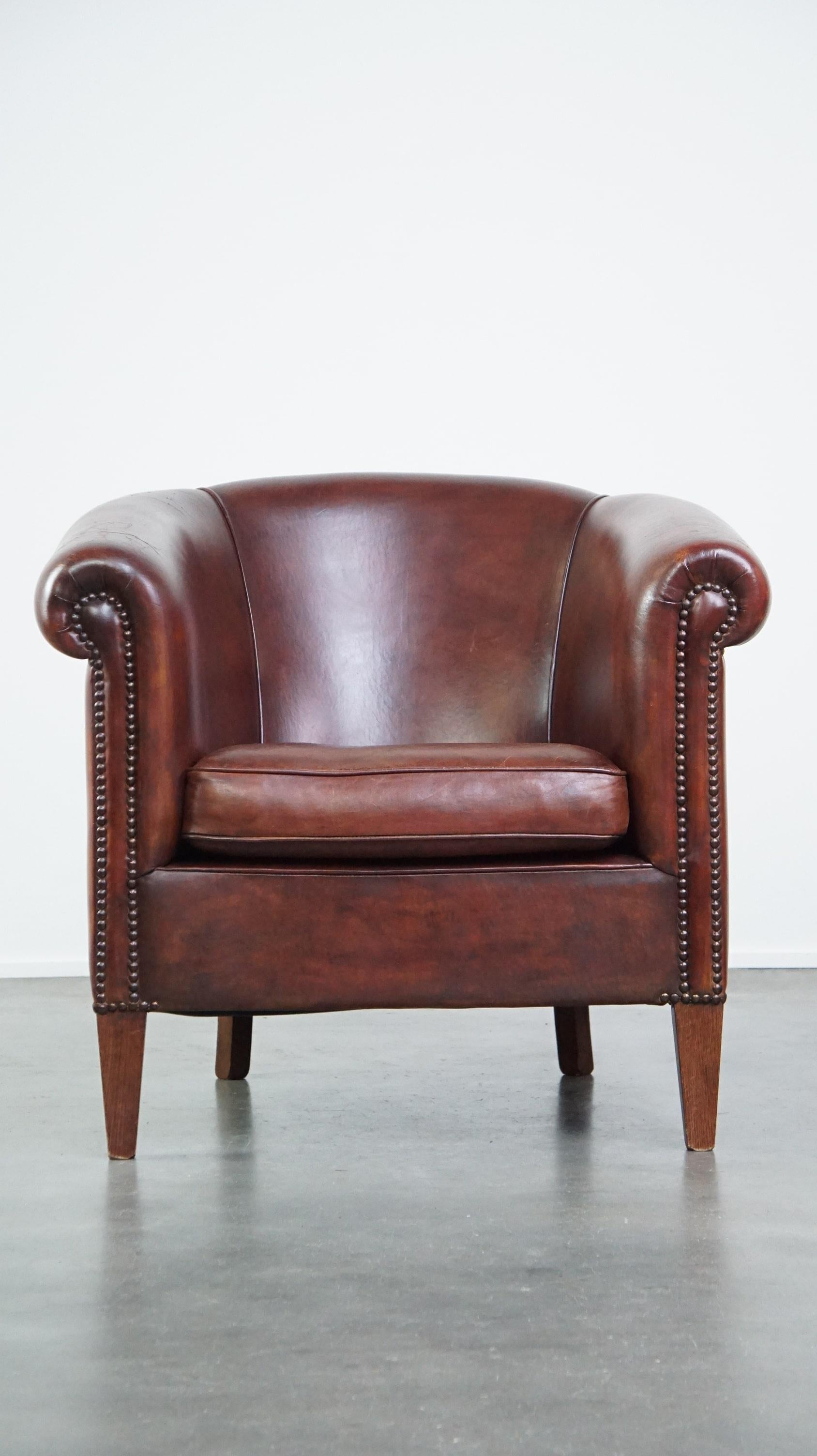 Offered: this charming and spacious sheepskin leather club armchair finished with decorative nails in English style.

This delightful sheepskin leather club armchair offers a comfortable and spacious seat, featuring a loose seat cushion and adorned