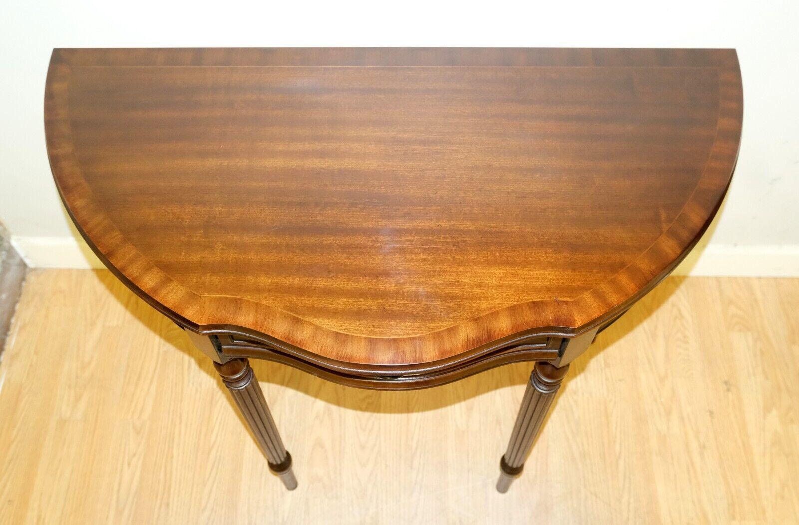 We are delighted to offer for sale this charming brown mahogany demi lune console table on reeded legs.

This versatile console/demi lune table is ideally shaped to decorate your hallway without taking up much space. The item is raised on four