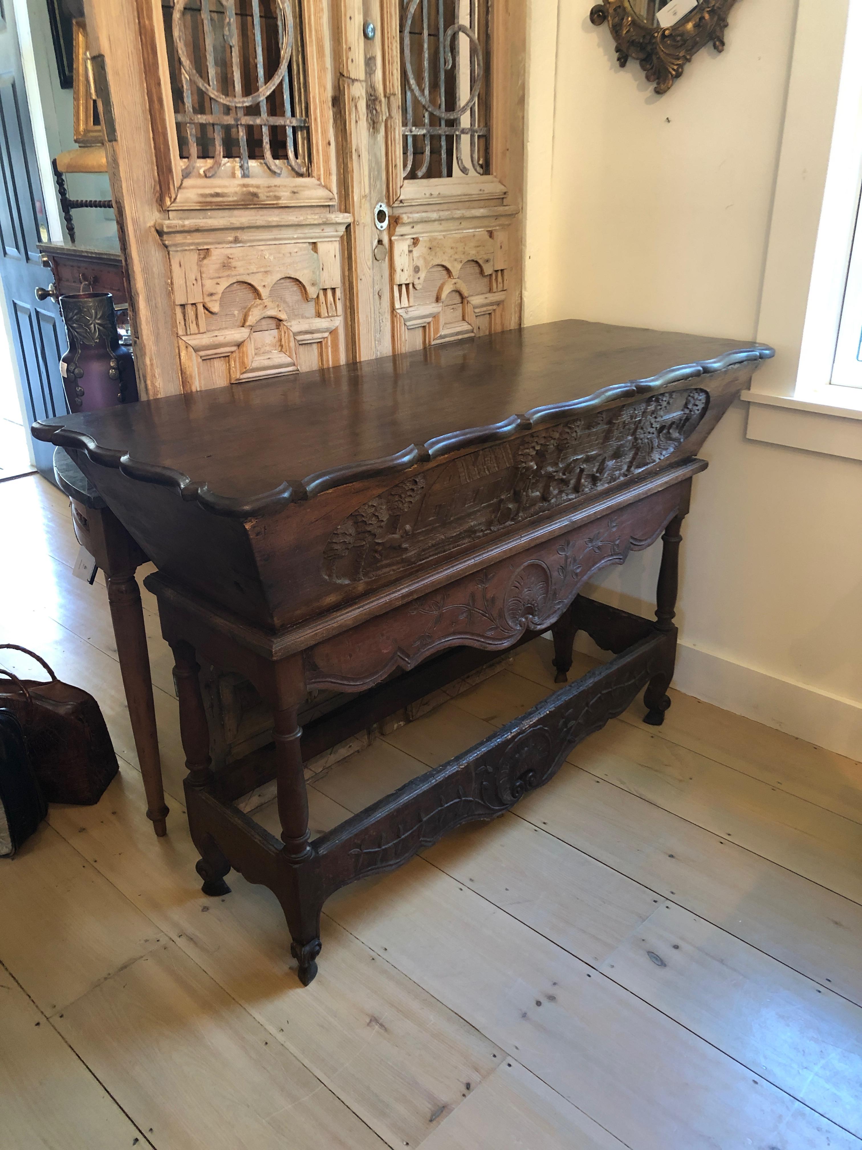 A gorgeous old Pelesia, Petrin or baker's bread table having wonderful hand carvings of figures, a town and decorative shapes with a removable top that reveals an interior storage chamber for bread. Makes a charming and rare console.